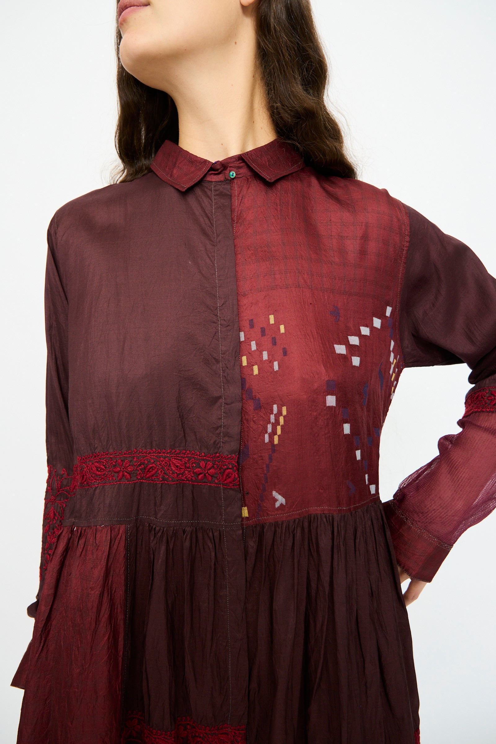 A woman models the Injiri Silk and Cotton Dress in Red, featuring geometric patterns and lace details, shown from shoulders to mid-thigh against a plain background.