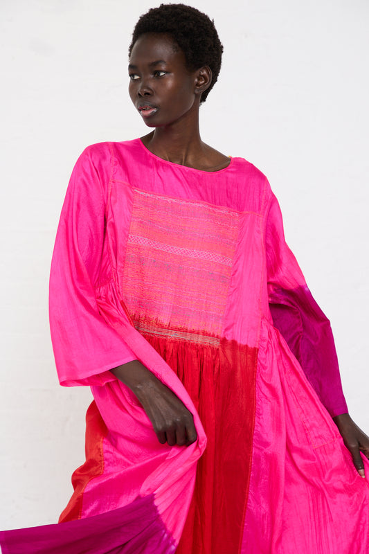 A woman in a vibrant pink color block Injiri silk dress with wide sleeves from the JODHPUR collection poses against a white background.