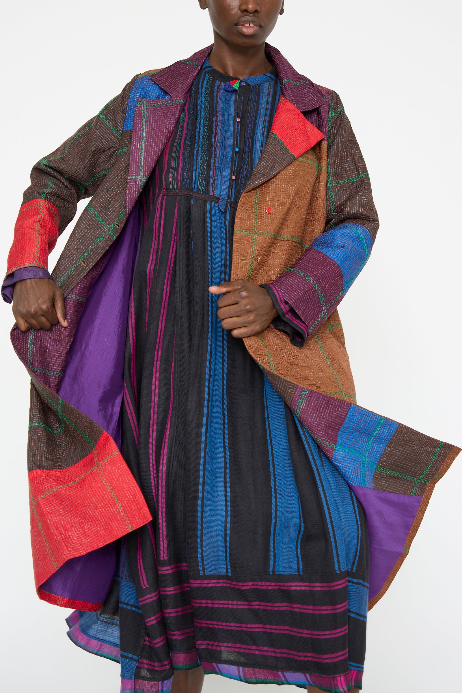 A person wearing the Injiri Silk Jacket in Brown and Multi over a blue and black striped dress stands against a plain background.