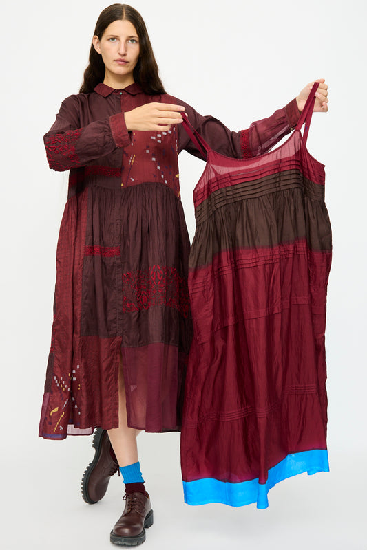 A woman displays the Injiri Silk and Cotton Slip Dress in Red, featuring a relaxed fit and blue hem, against a plain white background.