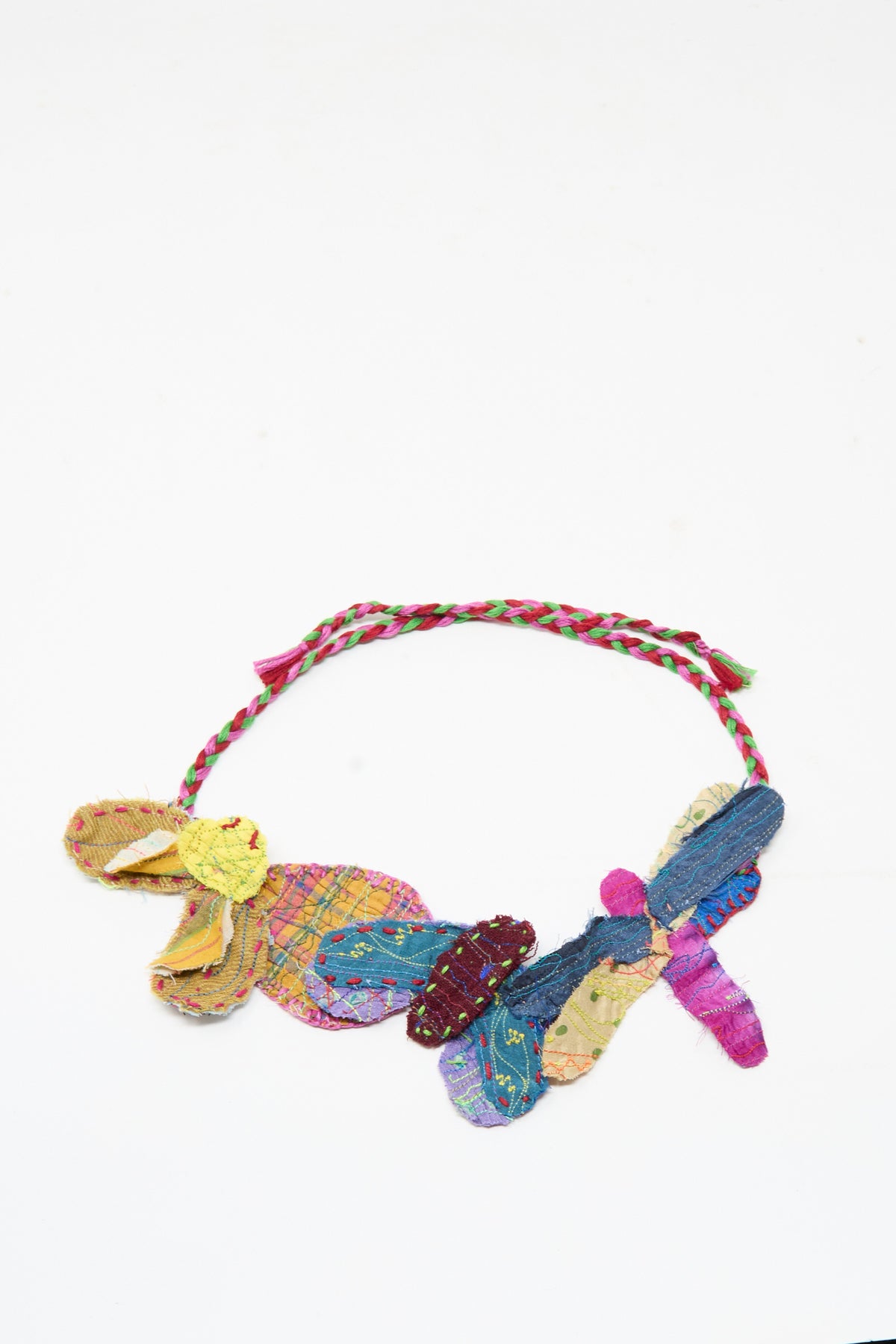 The Injiri Wool Silk Neckband in Multi features quilted butterfly shapes and a braided cord, evoking a vibrant flower patch design, shown against a white background.