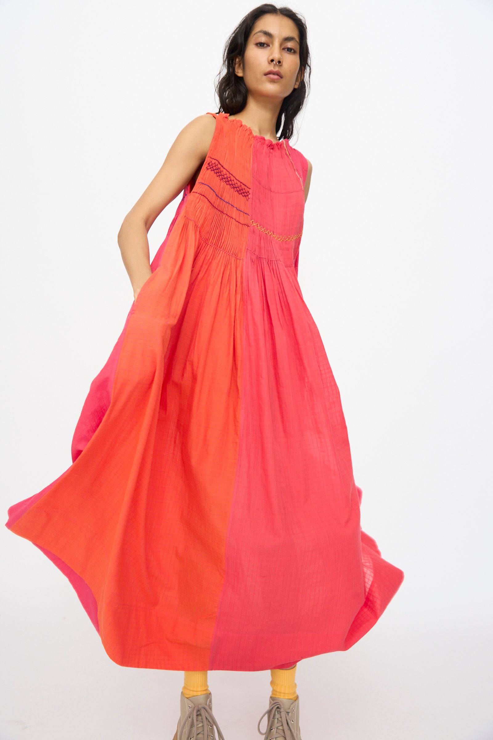 A woman models the Injiri Woven Cotton Dress in Pink and Red, a sleeveless, color-blocked midi dress, against a plain white background.
