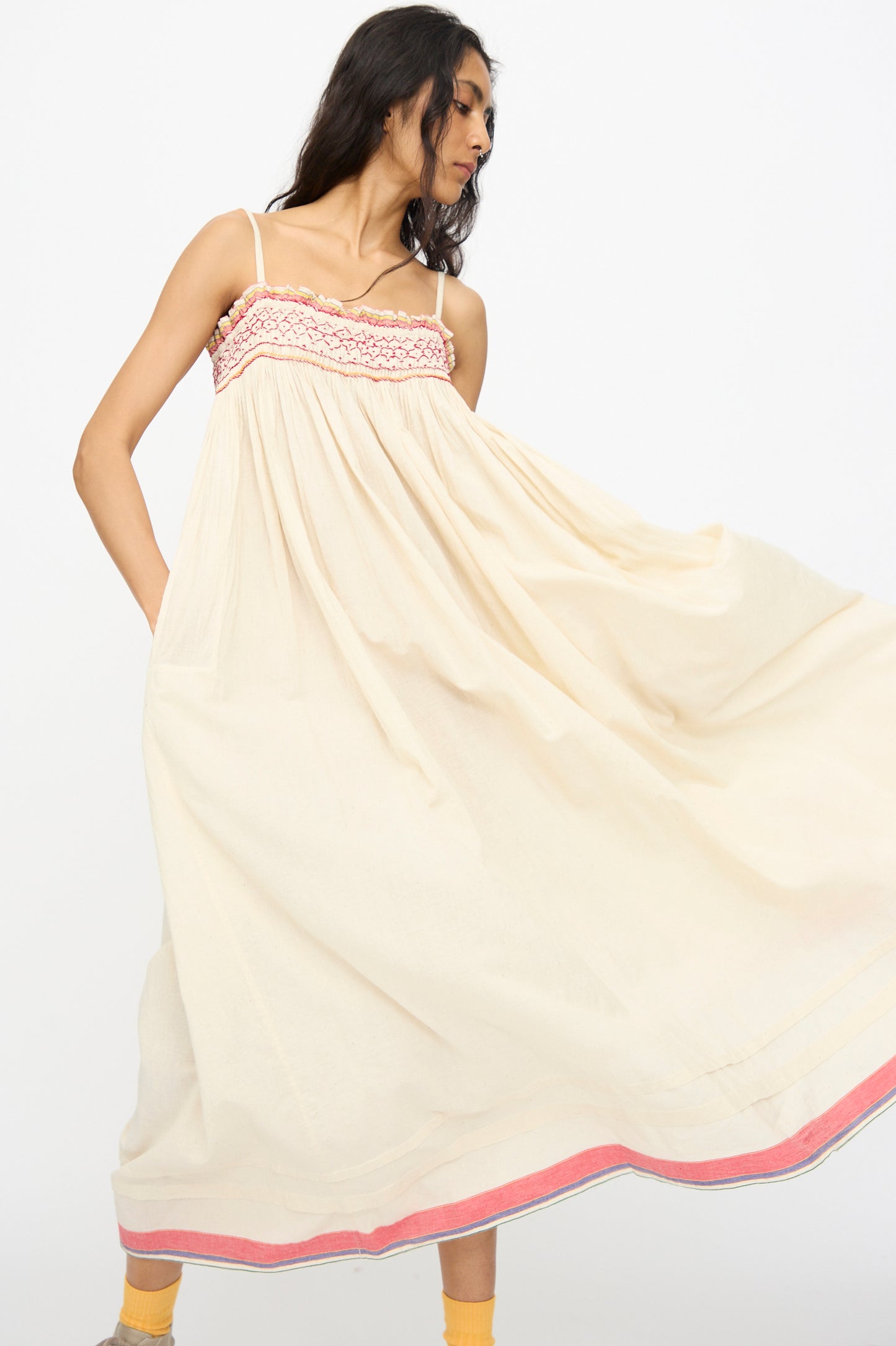 A woman models the Injiri Woven Cotton Slip Dress in white with red stitch, posing against a plain white background.