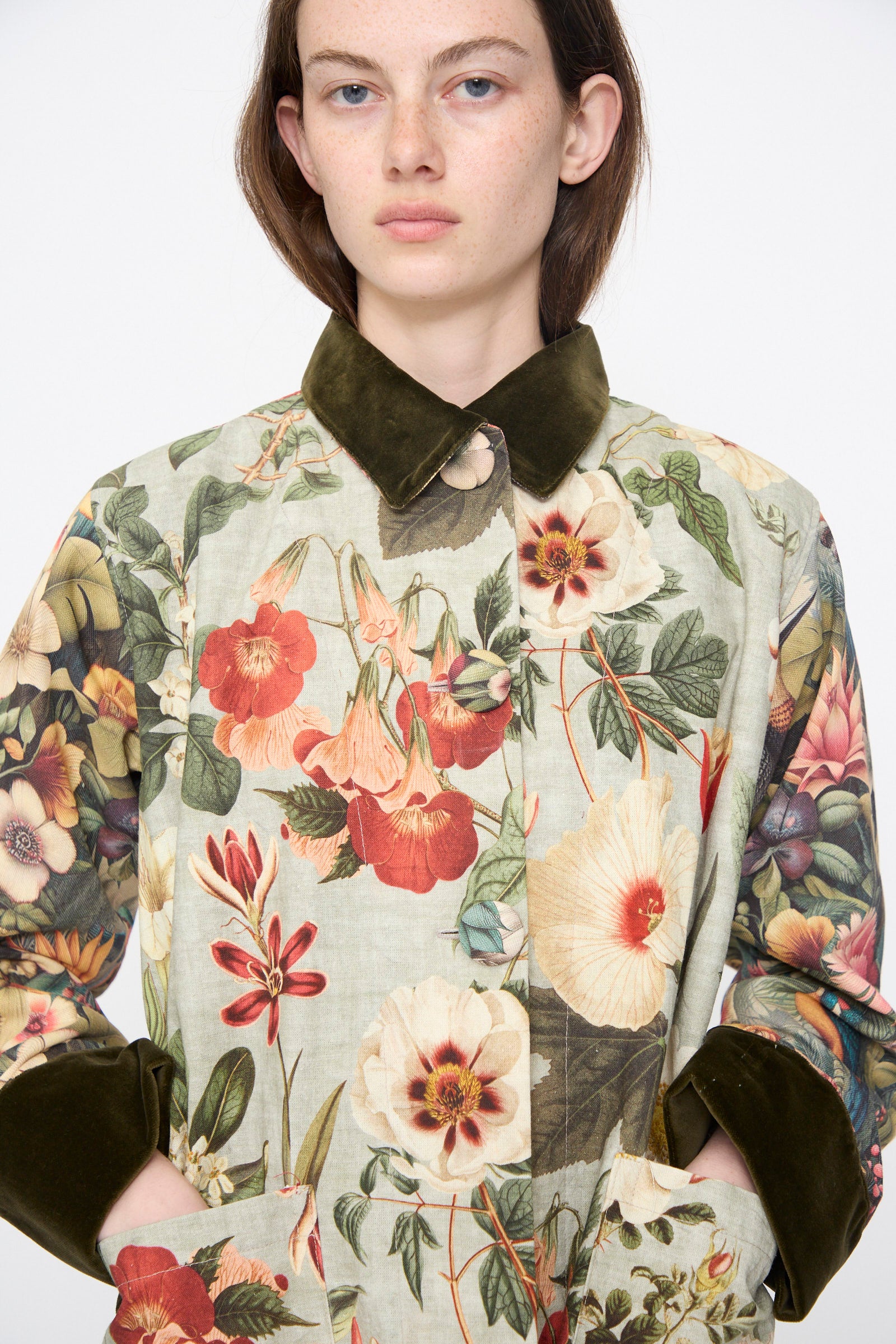 A person wearing the Intensity Cotton Coat with Velvet in Green Floral stands against a plain white background.