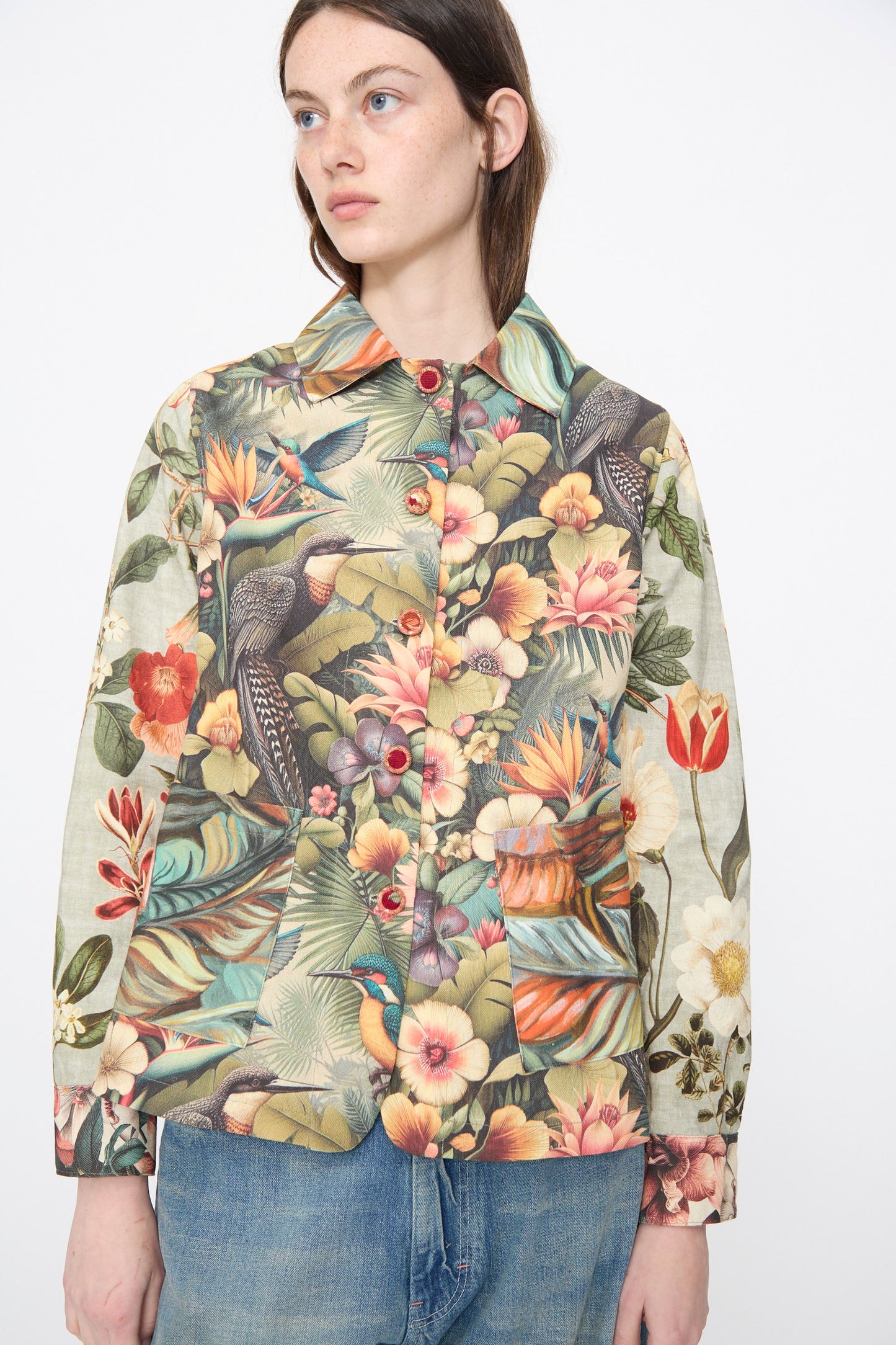 A person wears the Intensity Cotton Shirt Jacket in Green Floral paired with blue jeans, standing against a plain white background.