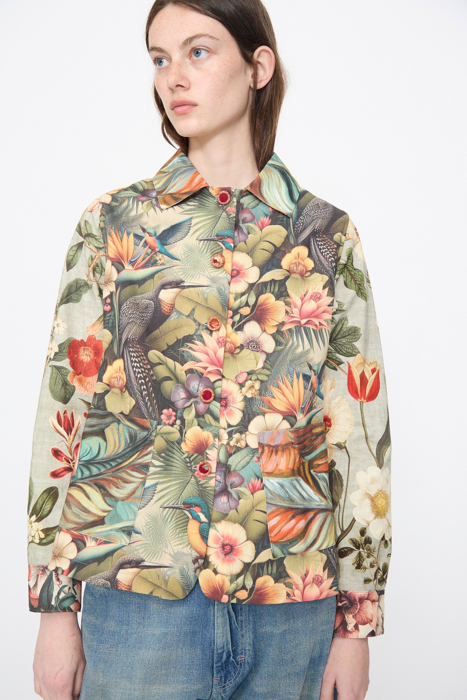 A person wears the Intensity Cotton Shirt Jacket in Green Floral paired with blue jeans, standing against a plain white background.