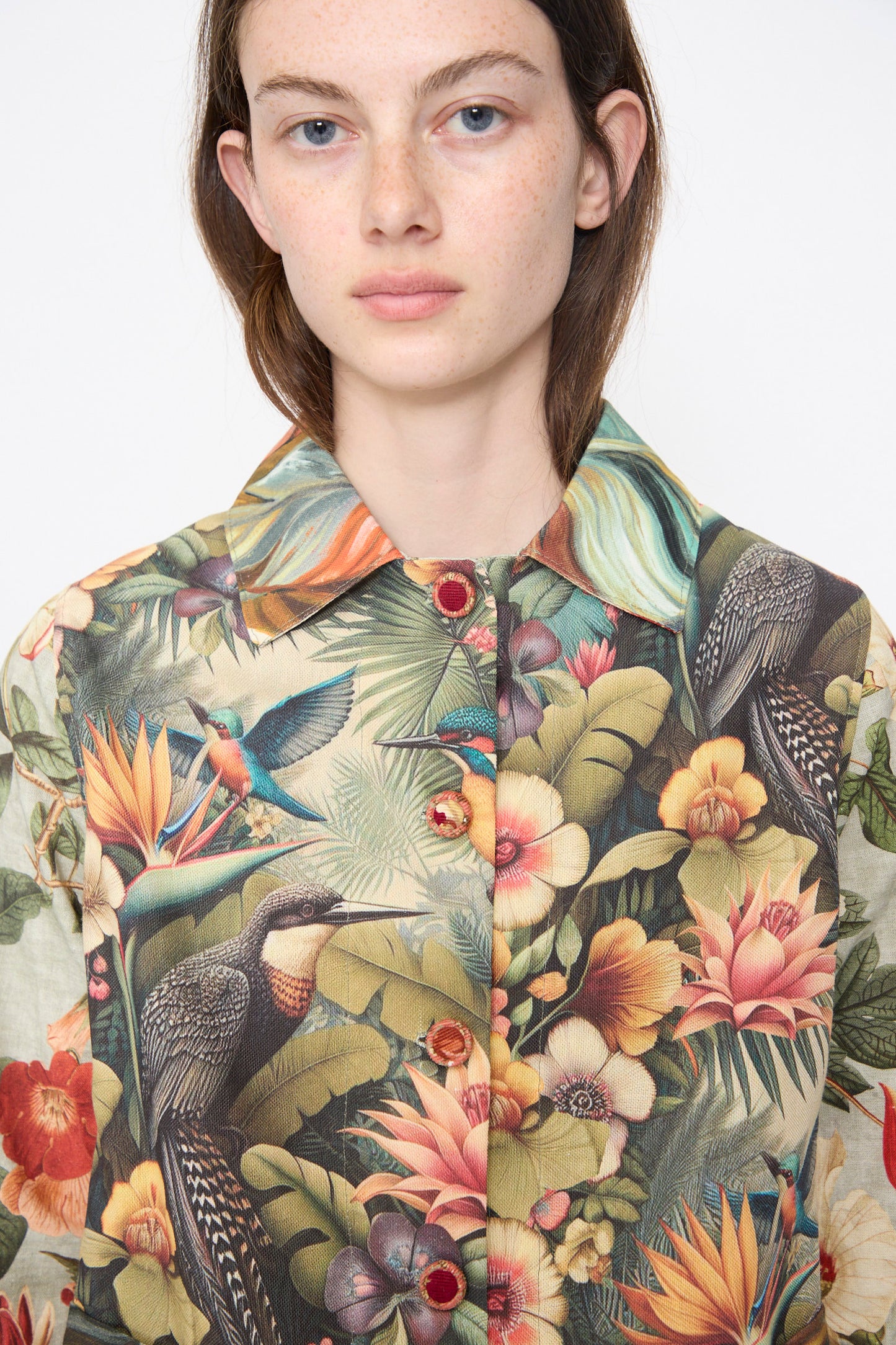 A person wears the Intensity Cotton Shirt Jacket in Green Floral, featuring a colorful tropical and bird print, against a plain white background.