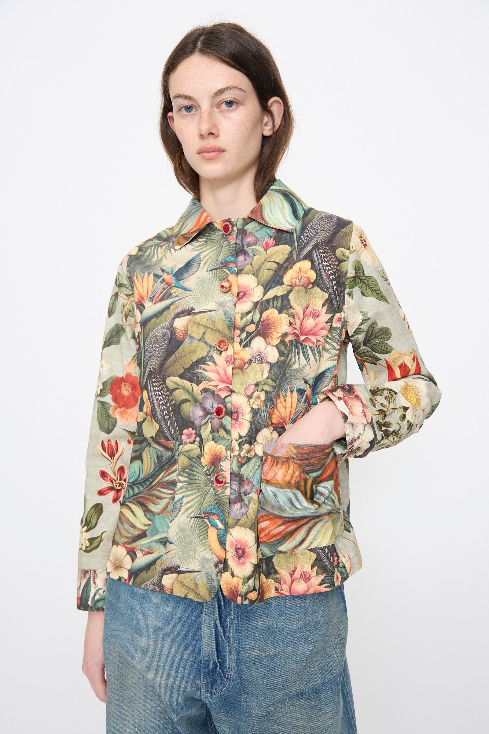 A person wears the Intensity Cotton Shirt Jacket in Green Floral with blue jeans, standing against a plain white background.