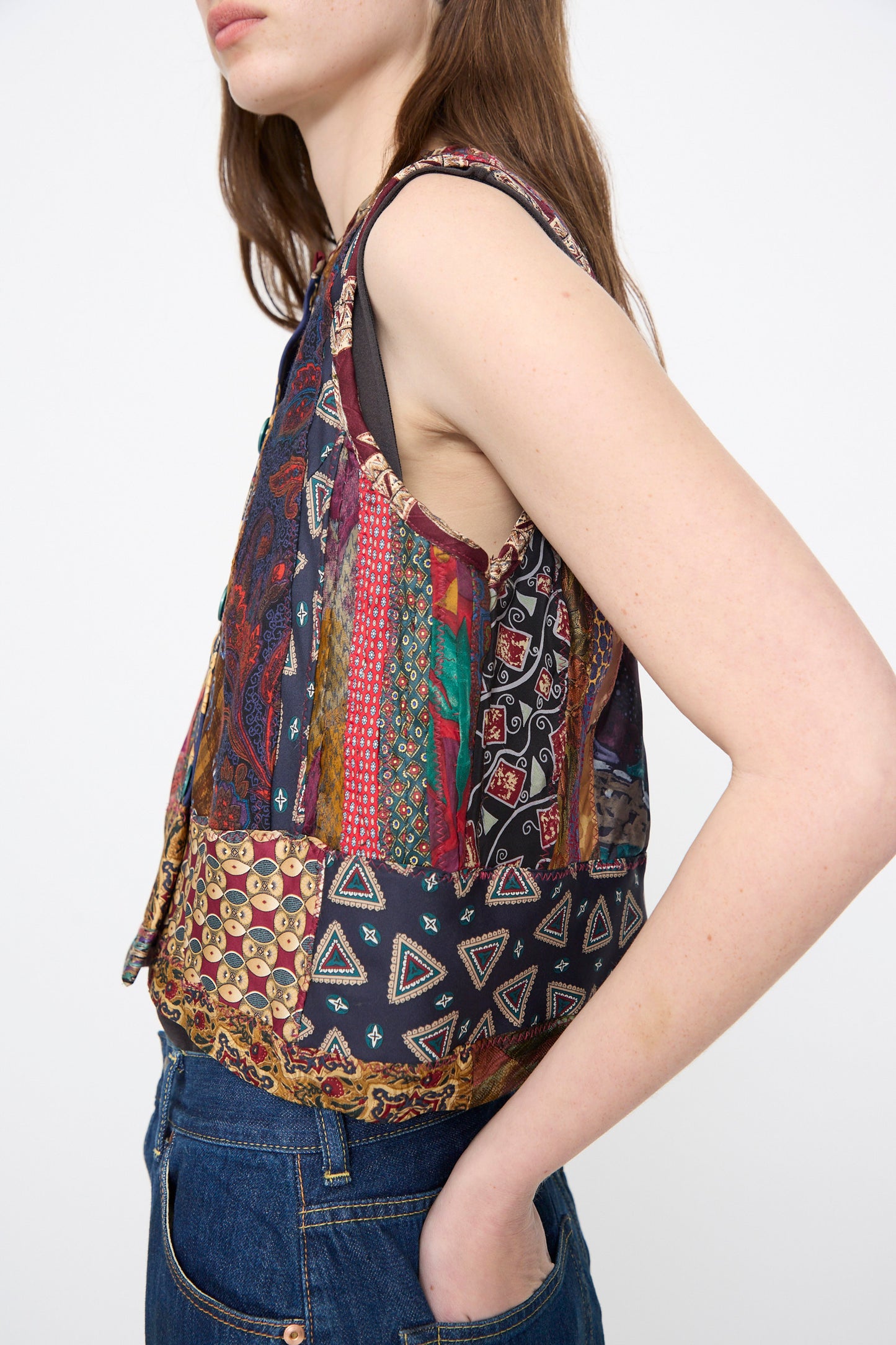 A person wearing the Intensity Ties Vest in Multi and blue jeans stands with one hand in their pocket against a plain background.