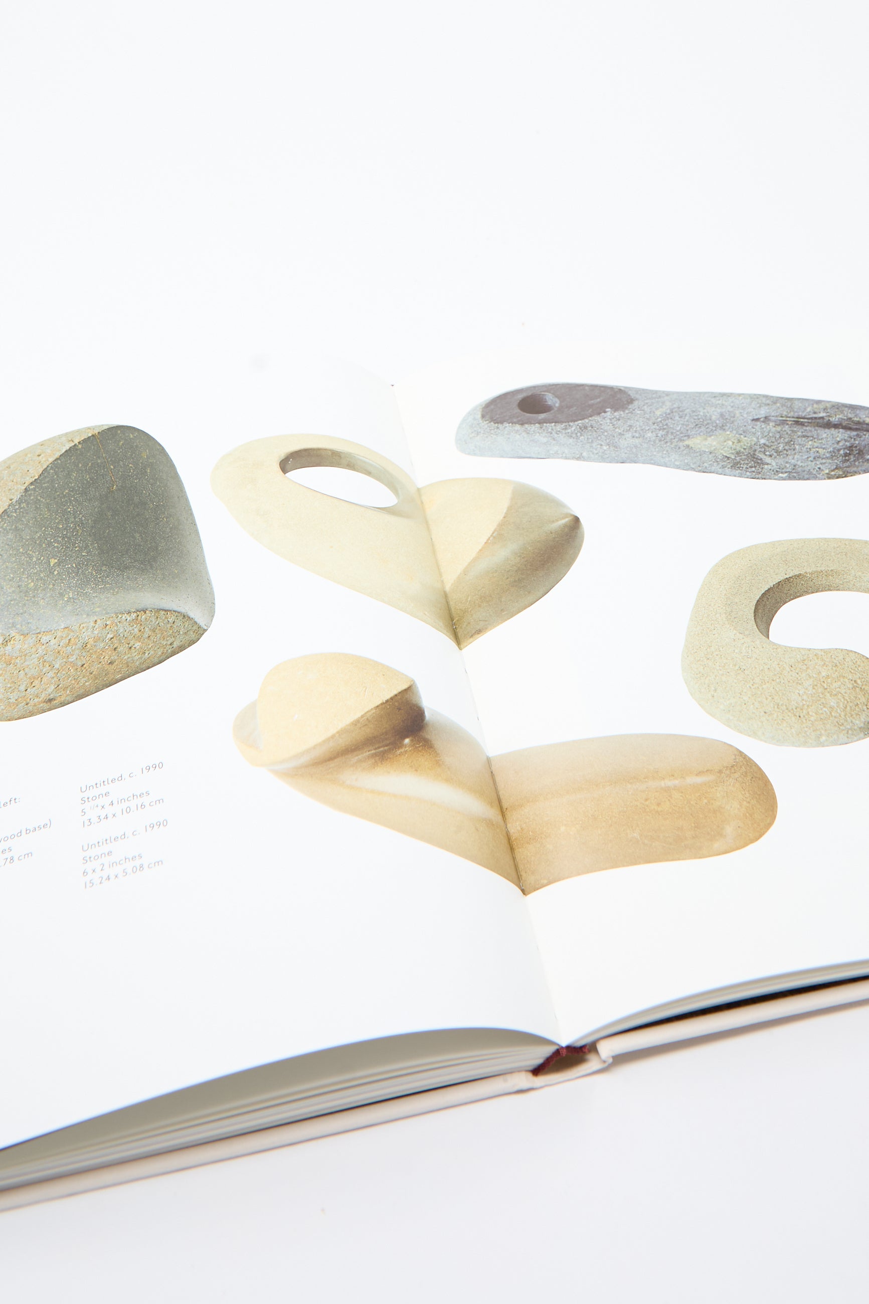 A copy of the Fourth Edition by JB Blunk displays images of abstract stone sculptures against a pristine white background, capturing the artist's practice through captivating archival photographs.