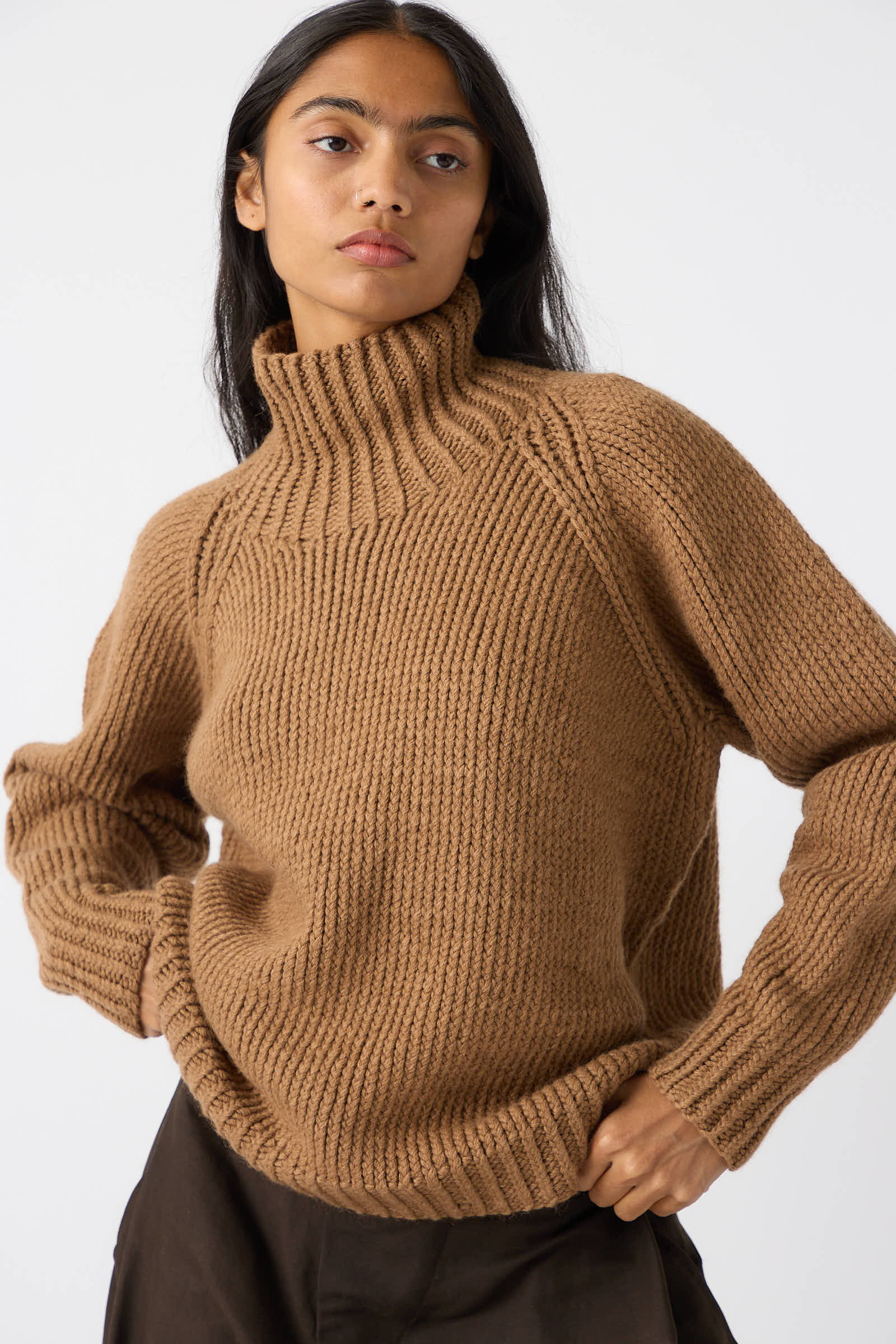 A person with long dark hair is wearing a chunky Jan-Jan Van Essche Camel Wool Knit Sweater in Natural. They are standing against a plain white background.