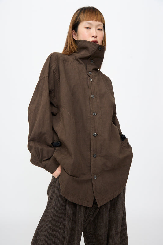 A person wearing a Jan-Jan Van Essche Cotton Wool Shirt #110 in Doro Zome, featuring an oversized fit, high collar, and dropped shoulders, styled with dark pleated trousers.