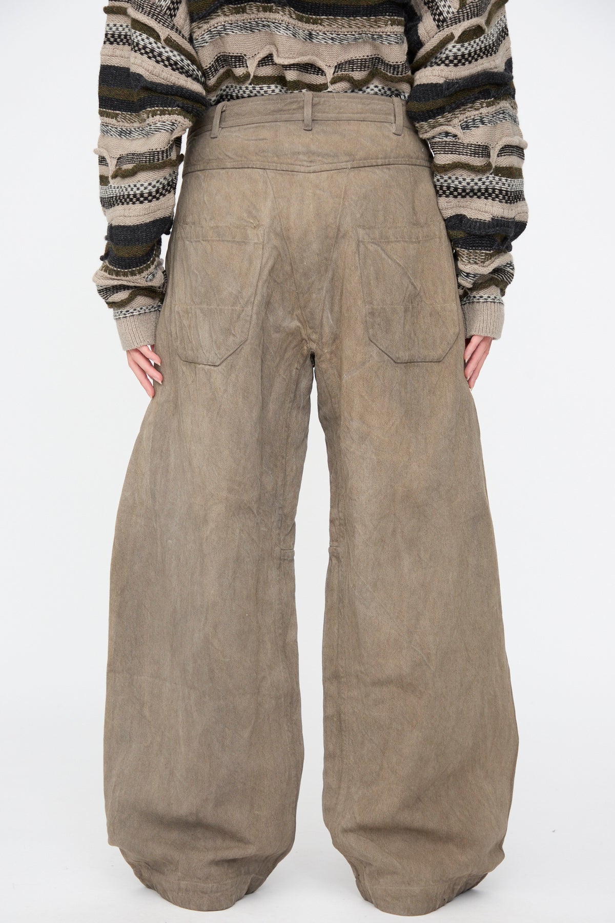Back view of a person wearing Jan-Jan Van Essche Hemp Bamboo Twill Trousers #90 in Kakishibu and Iron, styled with a patterned, oversized knit sweater.