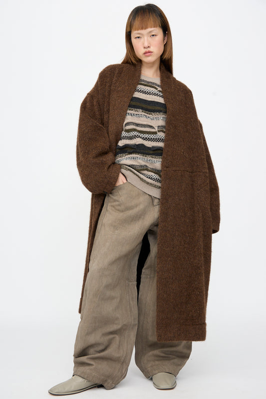 A person wearing a Jan-Jan Van Essche Highpile Herringbone Coat #35 in Brown Alpaca over a textured, patterned sweater and wide-leg trousers.