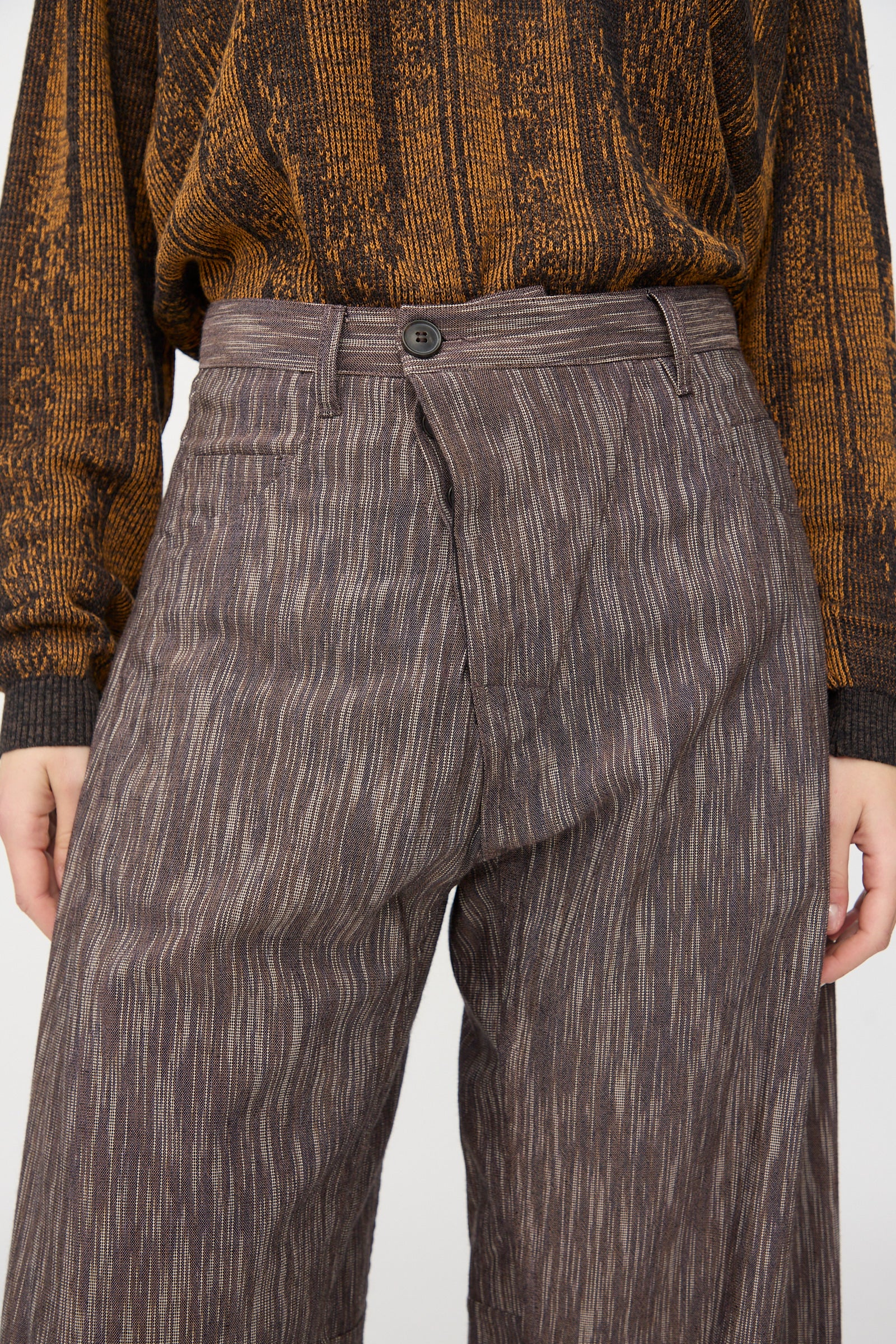 Person wears a textured brown and orange long-sleeve top tucked into Jan-Jan Van Essche Kasuri Cotton Silk Trousers #90 in Old Lavender, featuring a high-waisted, relaxed fit and straight leg.