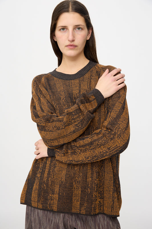 A person with long brown hair wears the Jan-Jan Van Essche Linen Cotton Kasuri Knit #77 in Black Brown Orange, standing against a plain white background with one arm crossed over their chest.