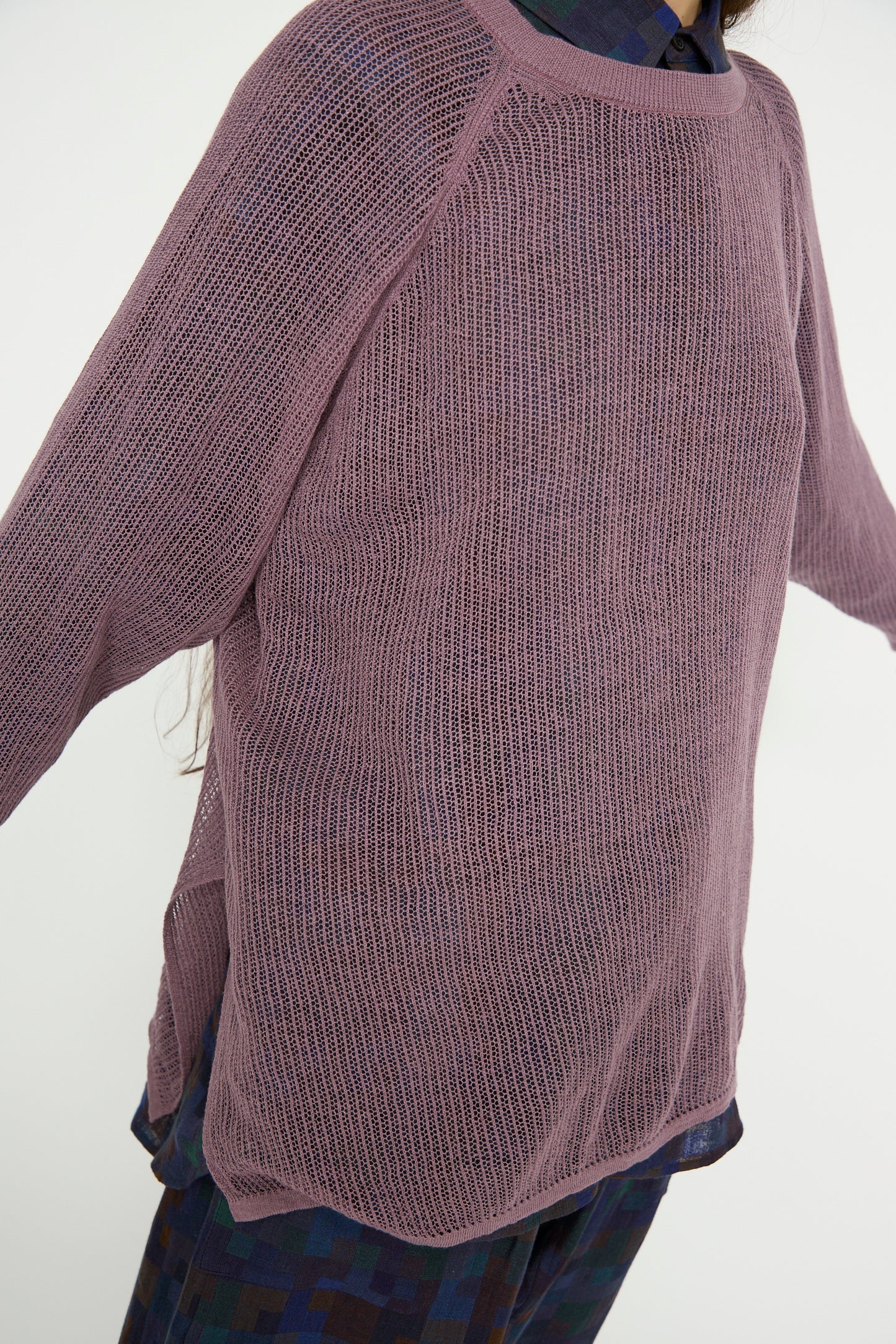 A person wearing Jan-Jan Van Essche's Linen Cotton Yarn Knit #69 in Lavender, stylishly draped over a dark patterned shirt with arms extended to the sides.