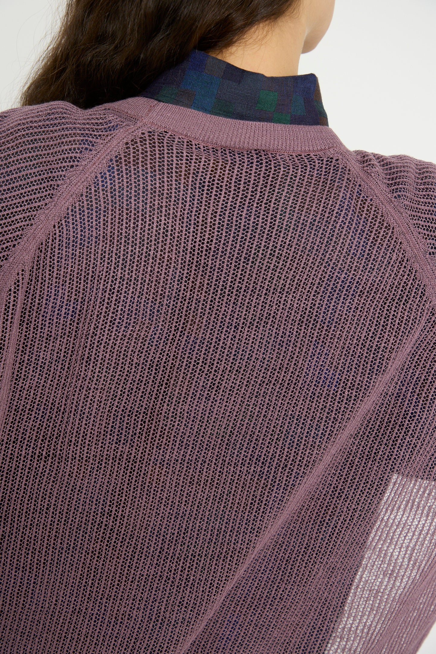 A close-up showcases a person wearing Jan-Jan Van Essche's Linen Cotton Yarn Knit #69 in Lavender over a patterned shirt, emphasizing the fabric texture.