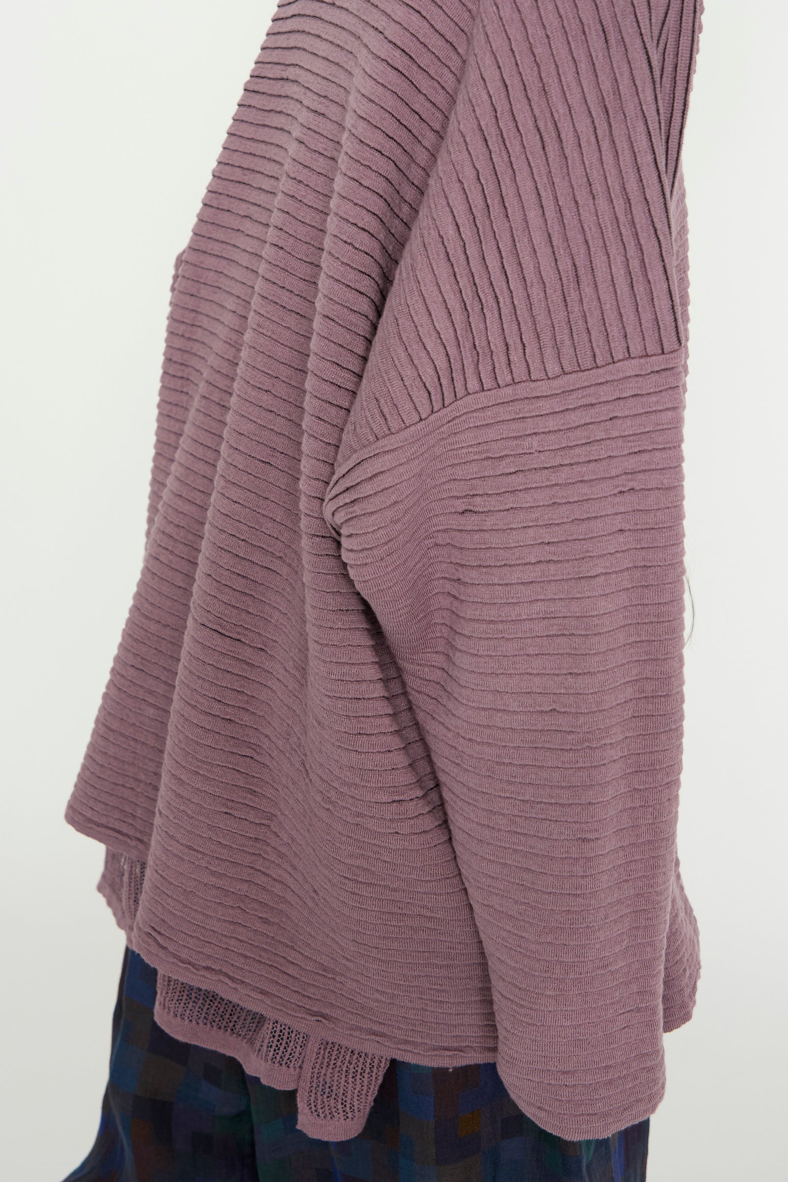 The Linen Cotton Yarn Knit #70 in Lavender by Jan-Jan Van Essche, with its oversized design and striped texture, pairs elegantly with a plaid skirt, highlighting the intricate fabric details.