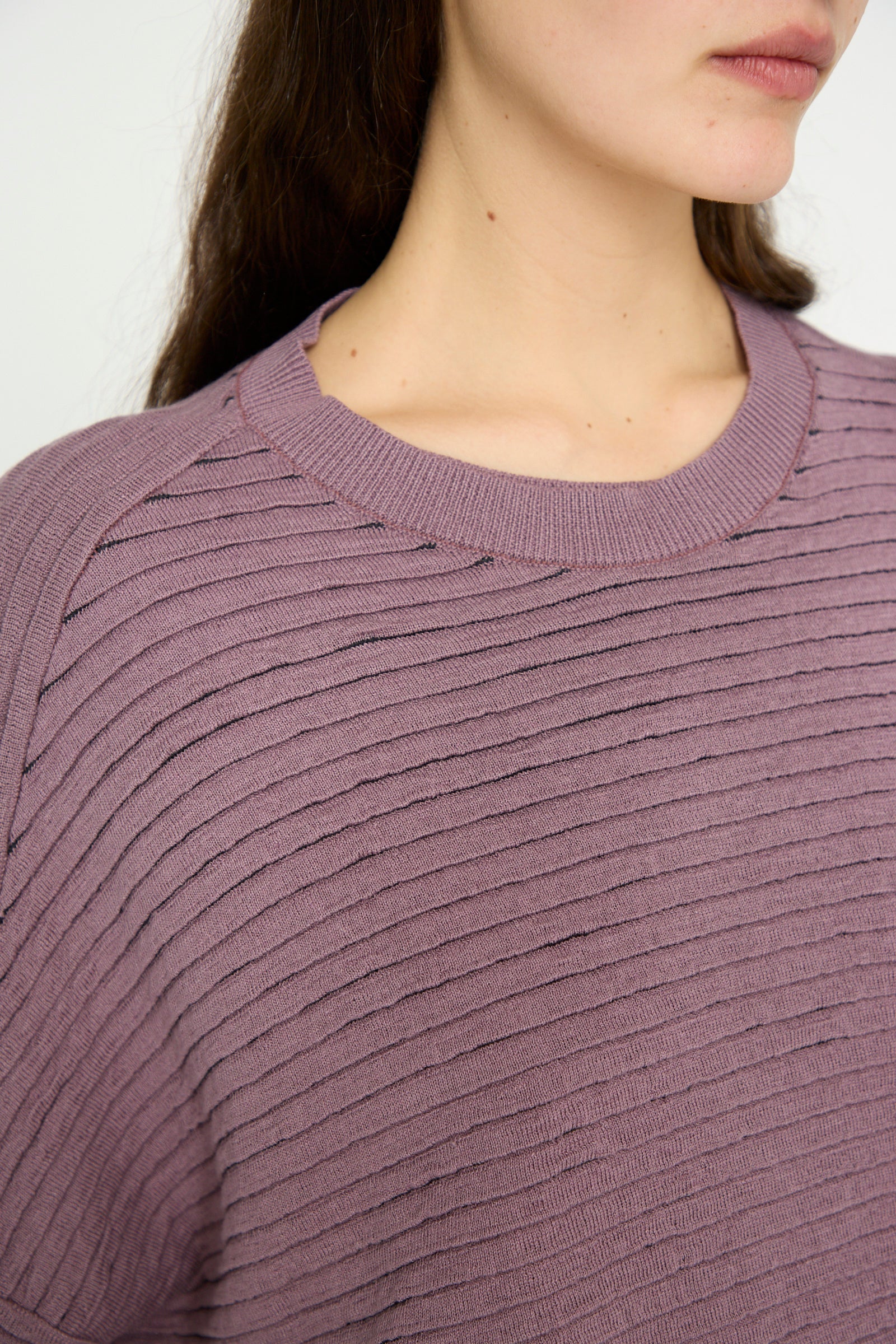 Someone wearing Jan-Jan Van Essche's Linen Cotton Yarn Knit #70 in Lavender, featuring a ribbed texture from neck to mid-torso, with long brown hair visible.