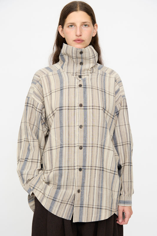 A person wearing the Jan-Jan Van Essche Madras Plaid Shirt #110 in Plaster, featuring a beige and gray plaid cotton blend and high collar, stands against a plain white background.