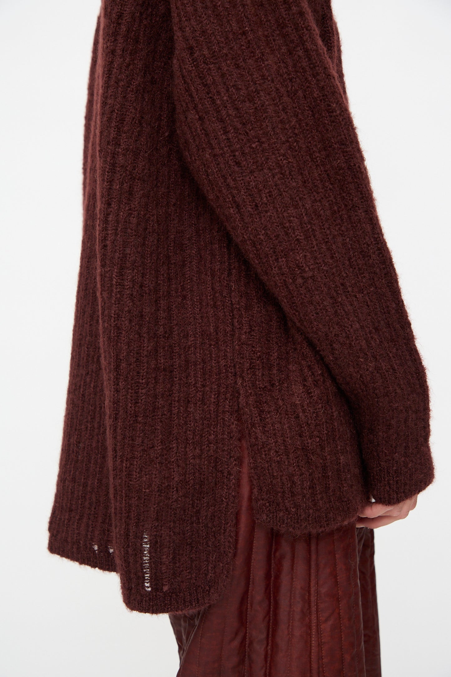 A person is shown from the side against a plain background wearing the Jan-Jan Van Essche Mohair Knit #71 Sweater in Oxblood, styled with a reddish-brown pleated skirt.