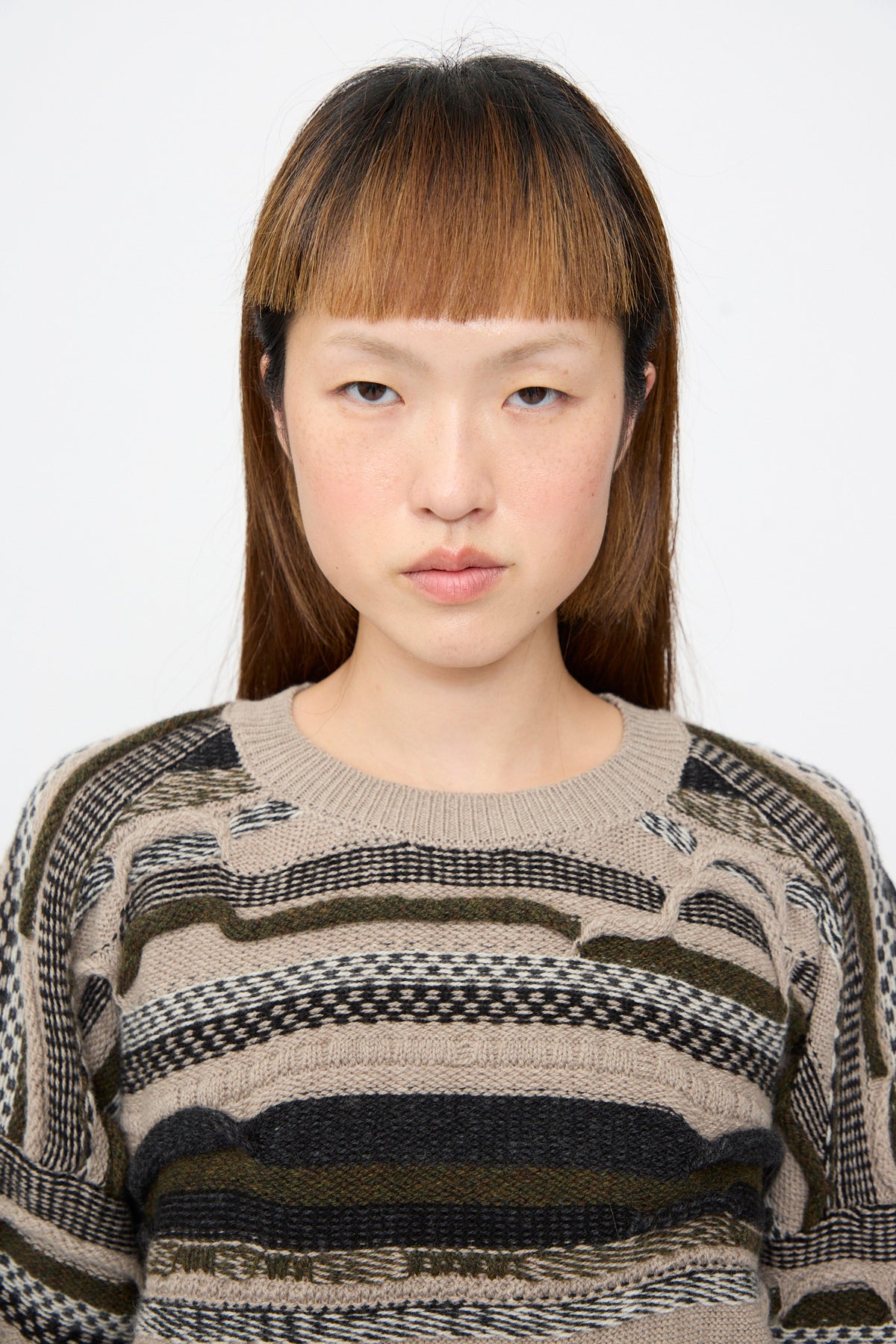 A person wearing a Jan-Jan Van Essche Super Fine Wool Knit Sweater #80 in Light Variation, featuring an oversized, crew-neck, textured, multi-colored horizontal striped design.