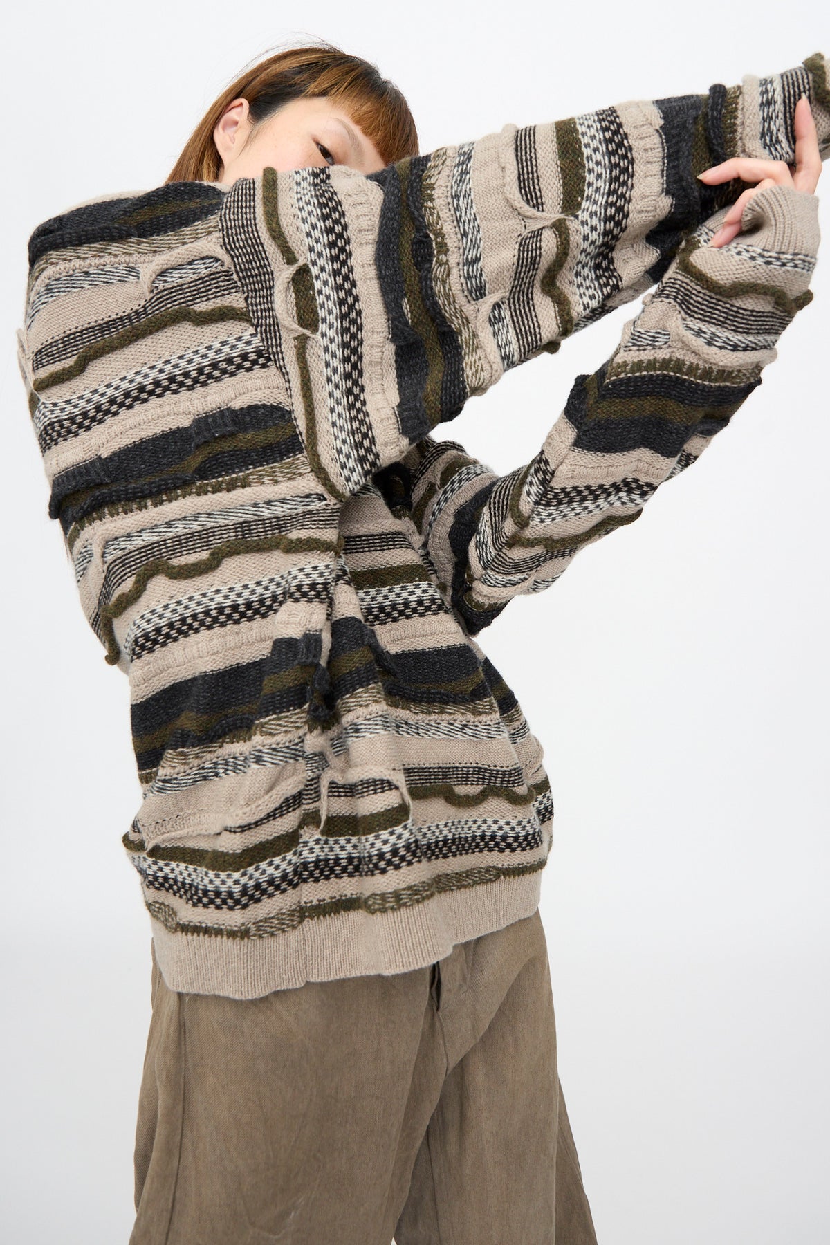 A person wearing a Jan-Jan Van Essche Super Fine Wool Knit Sweater #80 in Light Variation, an oversized, multi-textured knit with horizontal, multi-colored stripes.