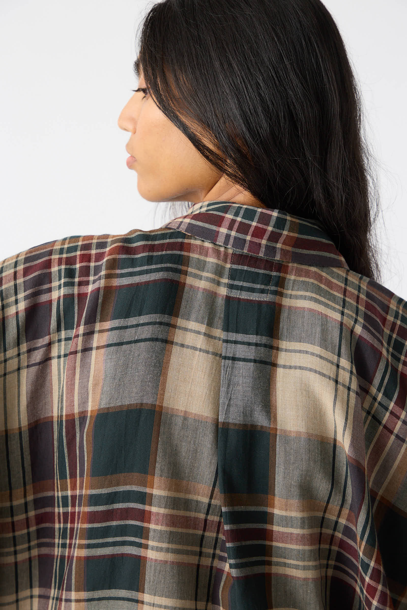 A person with long, dark hair is wearing a Jan-Jan Van Essche Viscose Shirt in Sand, Green and Burgundy. The image captures their back and part of their profile.