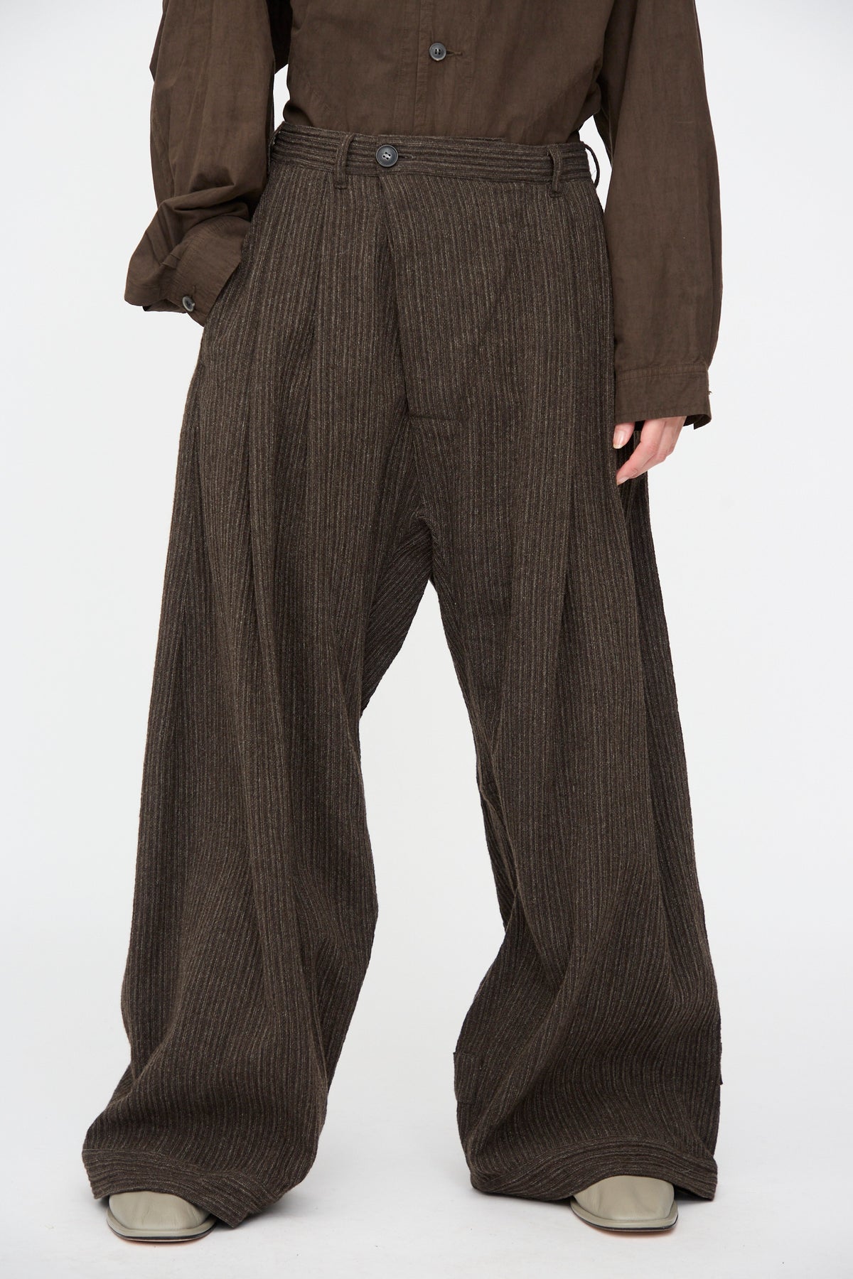 Jan-Jan Van Essche Yak Linen Cotton Trousers #93 in Brown Striped, featuring a double-pleated wide-leg fit worn with a tucked-in brown long-sleeve shirt.