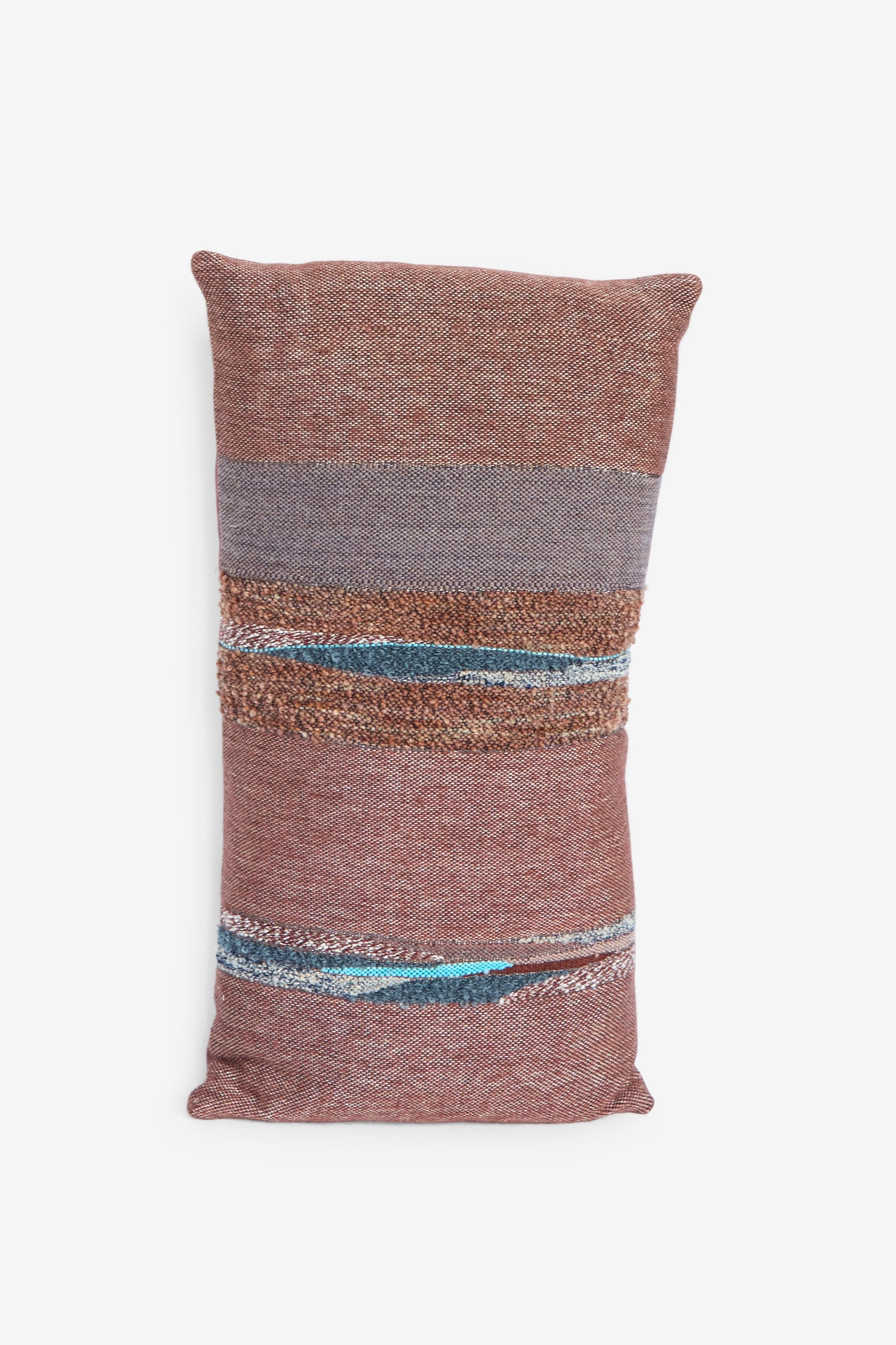 The Handwoven Rock Slab Pillow in Topaz and Copper by Jess Feury is a brown rectangular pillow featuring horizontal textured stripes in gray, beige, and blue on a white background. 