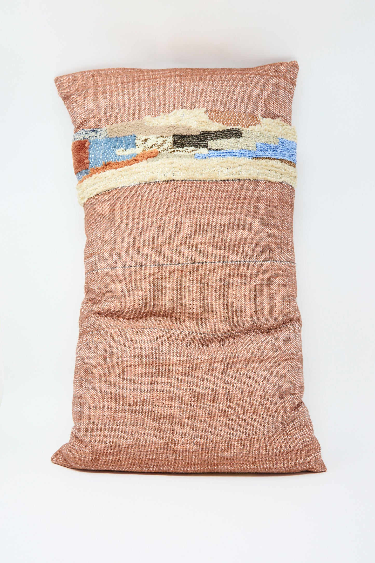 The Woven Colorblock Pillow in Persimmon and Clay by Jess Feury is a handmade rectangular cushion from California, featuring textured horizontal bands with abstract cream, blue, and brown patterns on a plain white background.
