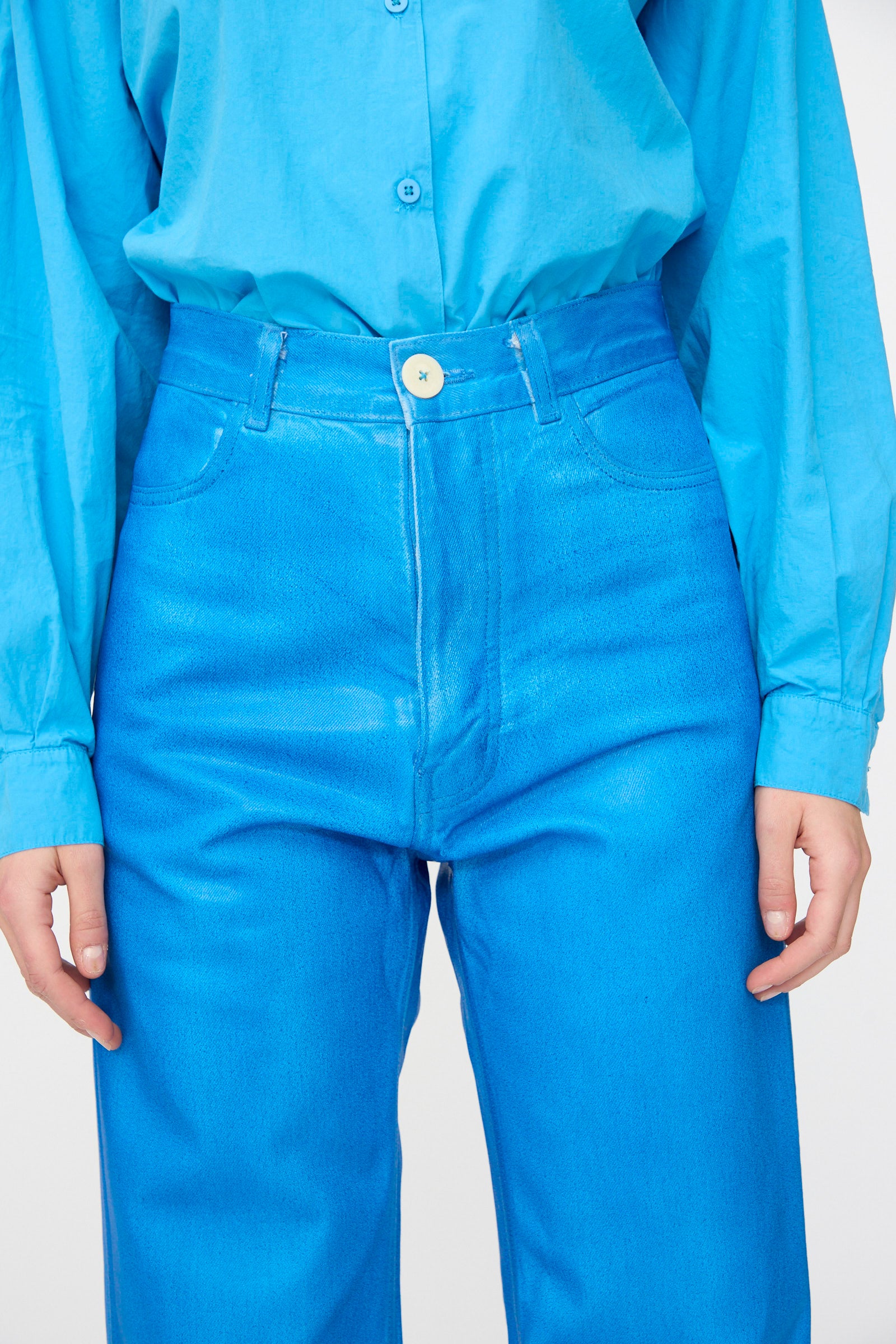 Model wears the Jesse Kamm 225 Jeans in Electric Blue Lacquer, high-rise Japanese denim, paired with a vibrant blue button-up shirt; shown from chest to mid-thigh with hands relaxed at their sides.