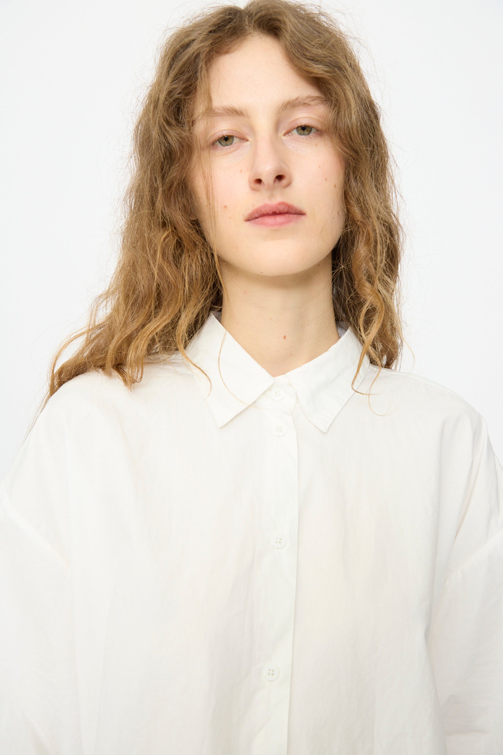 A person with wavy, light brown hair models the Jesse Kamm Alberta Shirt in Salt White, standing against a plain white background and looking straight at the camera.
