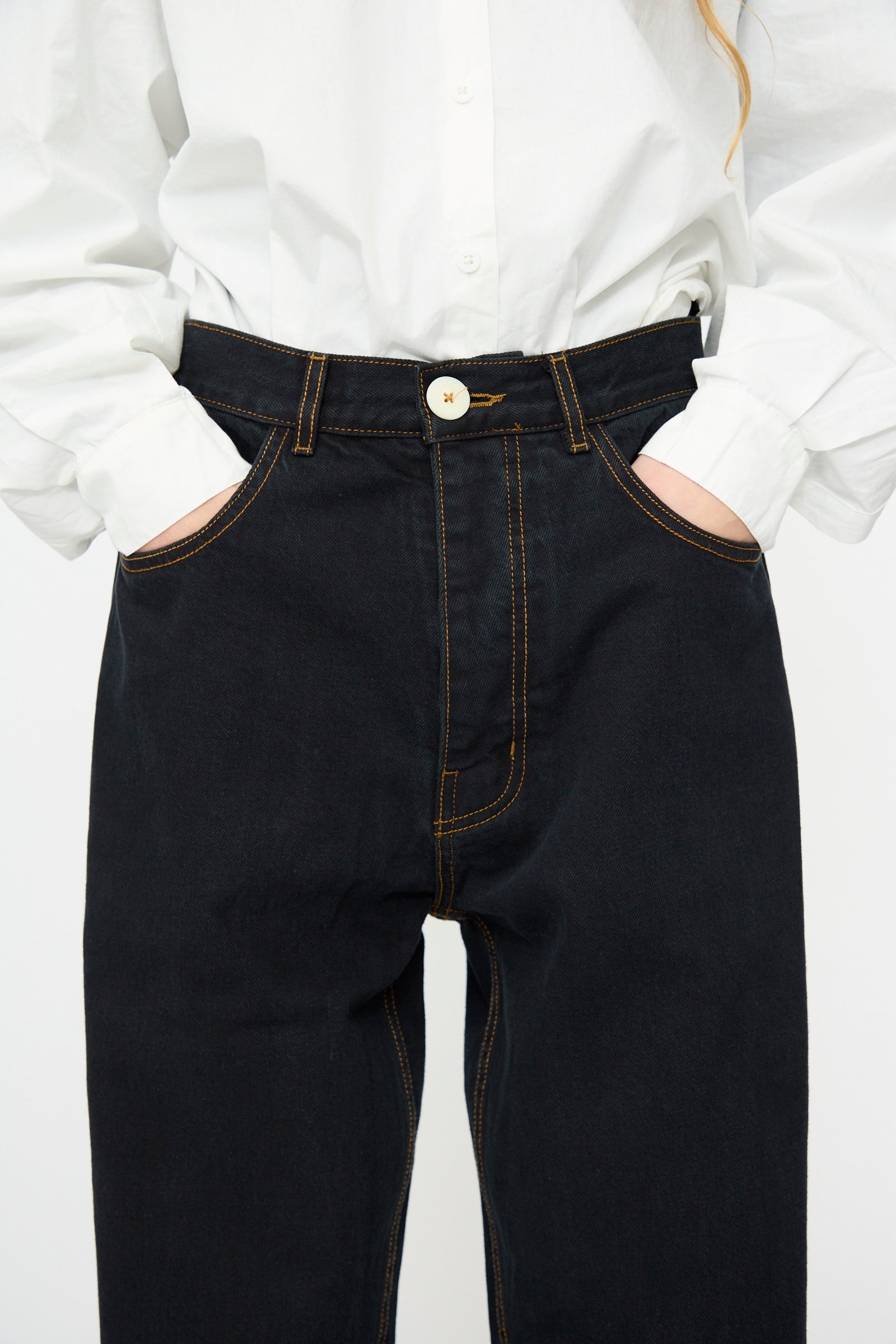 Person wearing a white button-up shirt and Jesse Kamm's California Wide in Black Overdye, shown from shoulders to thighs with hands in pockets.