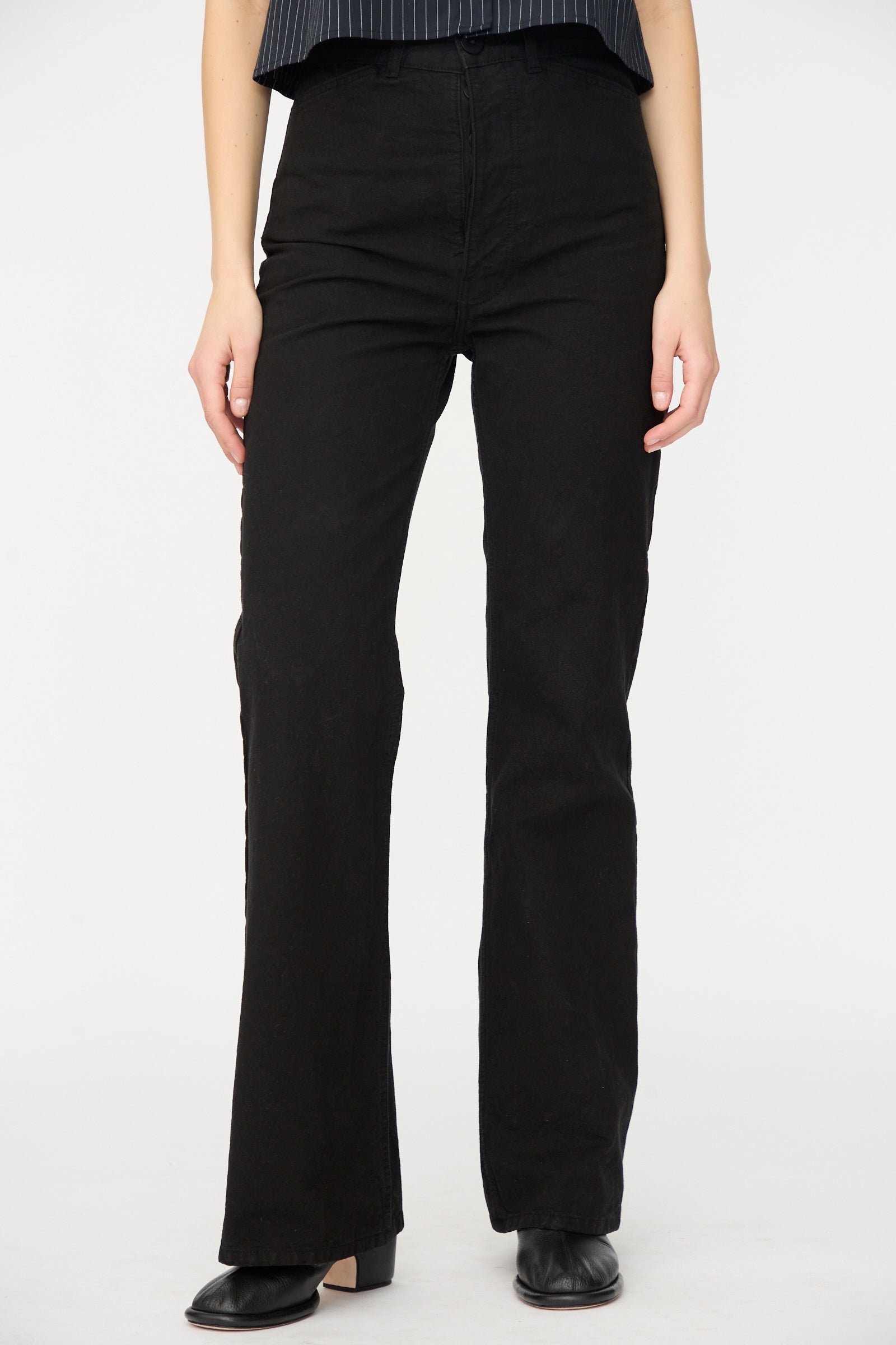 A person wears Jesse Kamm’s Canvas Les Deux Pants in Black, crafted from organic cotton canvas in California, paired with black shoes and photographed against a white background. The upper body is partially out of frame.