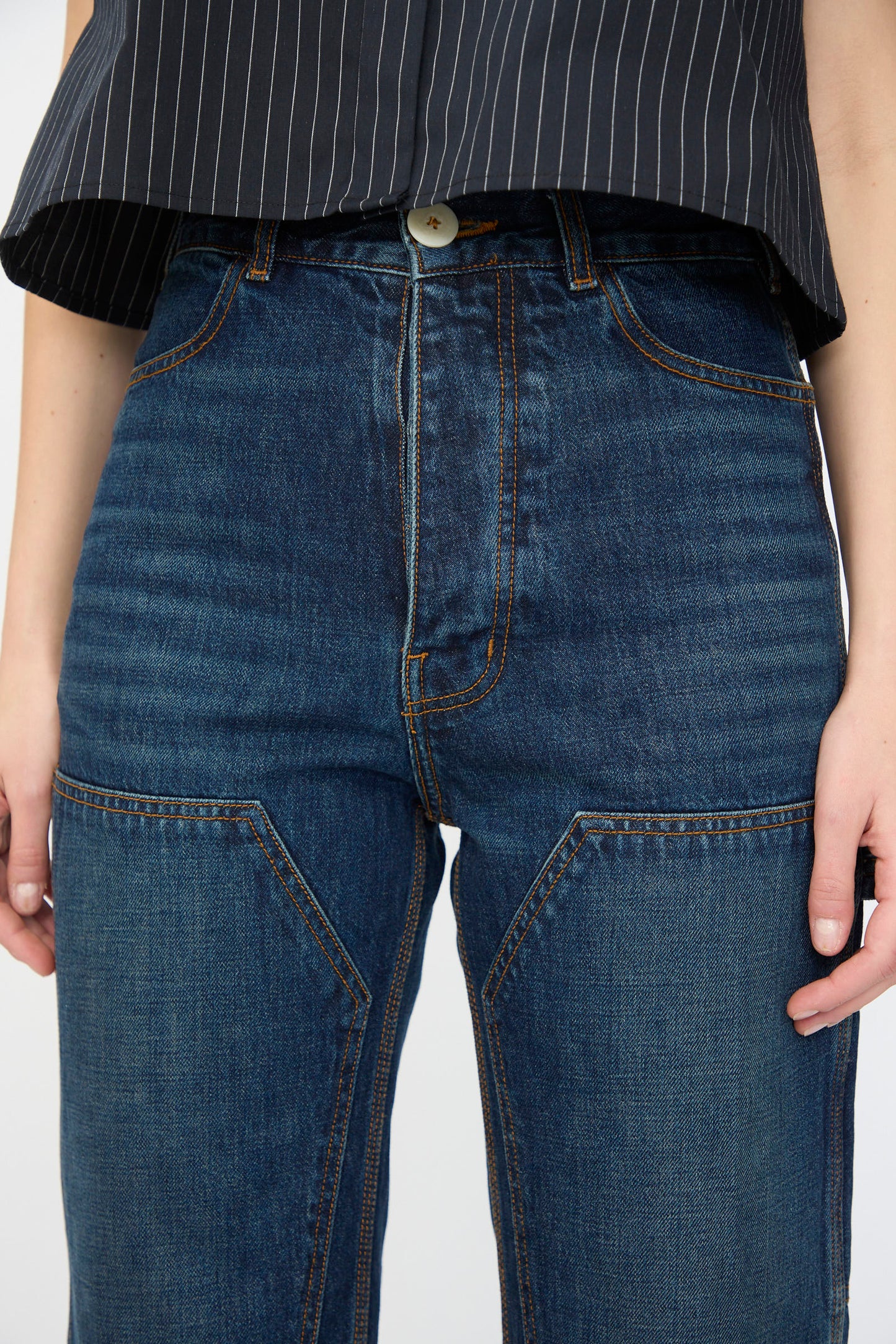 A person wearing Jesse Kamm’s Denim Patchwork Handy Pants in Medium Roast paired with a black pinstripe shirt.