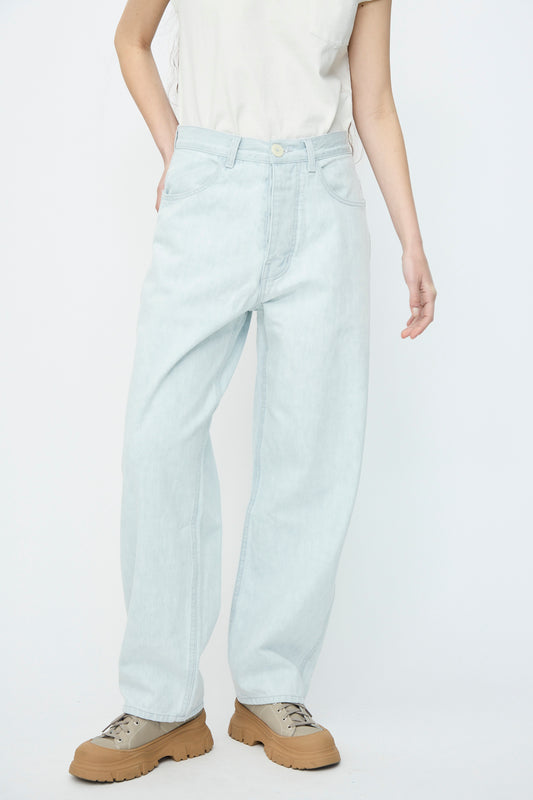 Wearing Jesse Kamm's Japanese Denim California Wide in Pale Blue, a person pairs them with a white t-shirt and tan shoes against a plain white background.