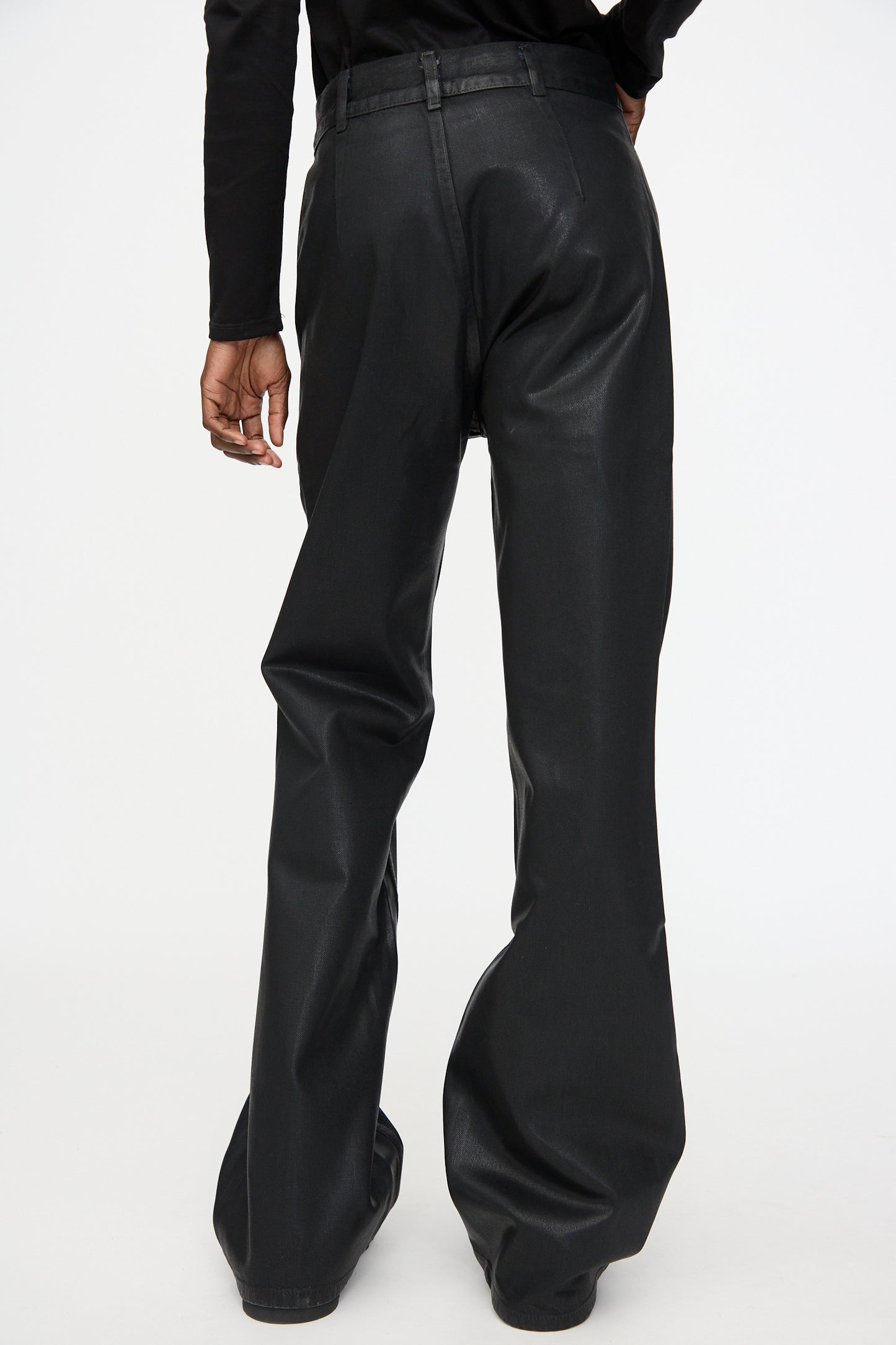 A person wearing Jesse Kamm Japanese Denim Les Deux Pants in Black Lacquer, paired with a black long-sleeve top, shown from the back against a plain white background.