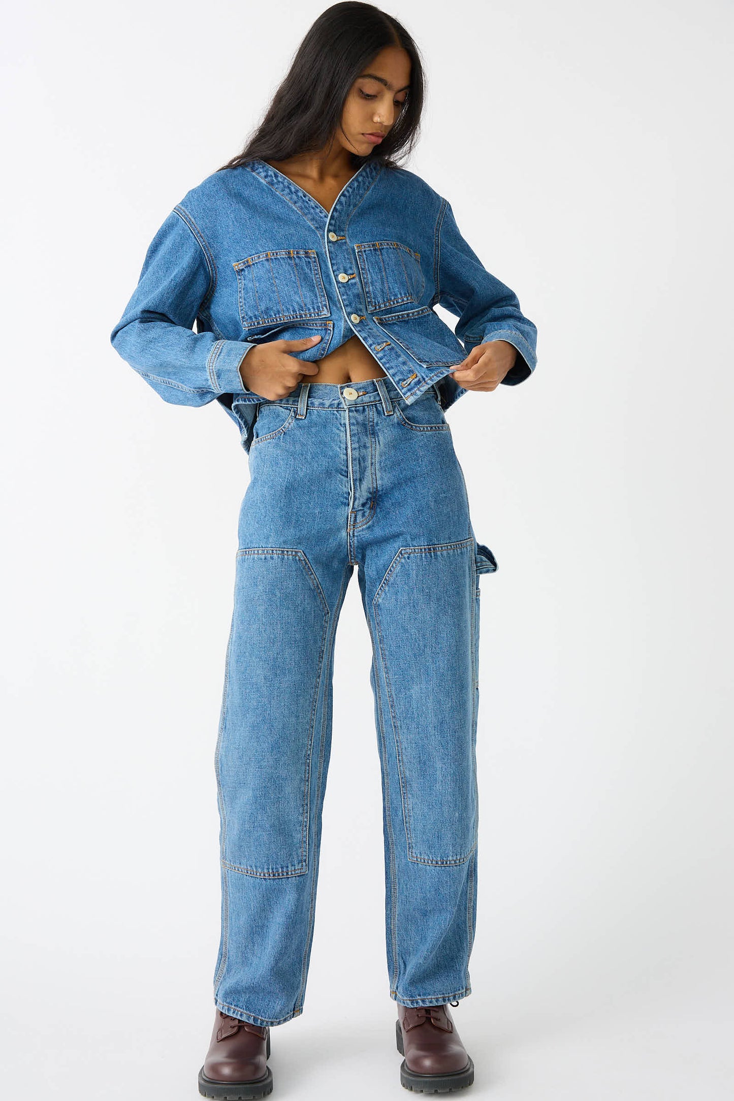 Person standing on a white background, adjusting their Japanese Denim Patchfront Handy Pant in Cowboy Blue by Jesse Kamm.