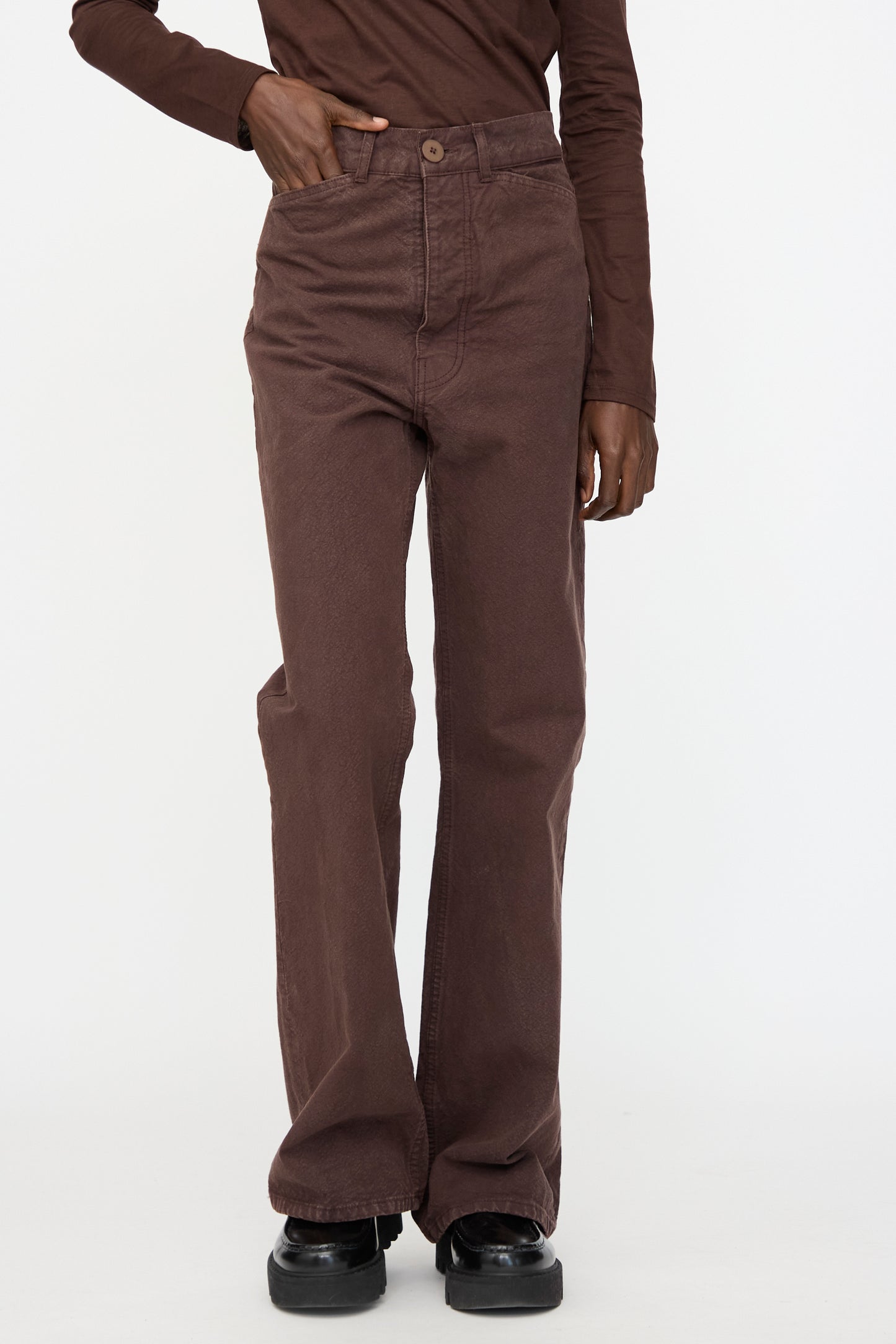 A person wears Jesse Kamm's Organic Canvas Les Deux Pants in Raisin with a matching long-sleeve top and black shoes, standing against a plain white background.