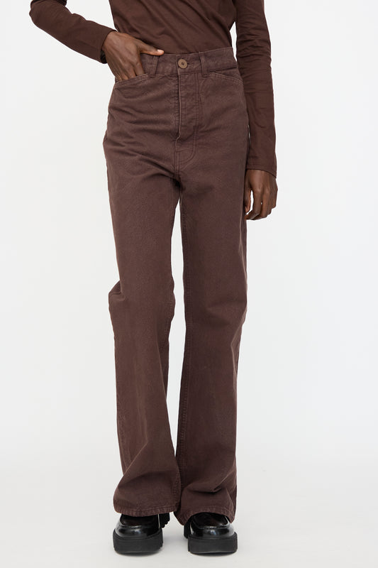A person wears Jesse Kamm's Organic Canvas Les Deux Pants in Raisin with a matching long-sleeve top and black shoes, standing against a plain white background.