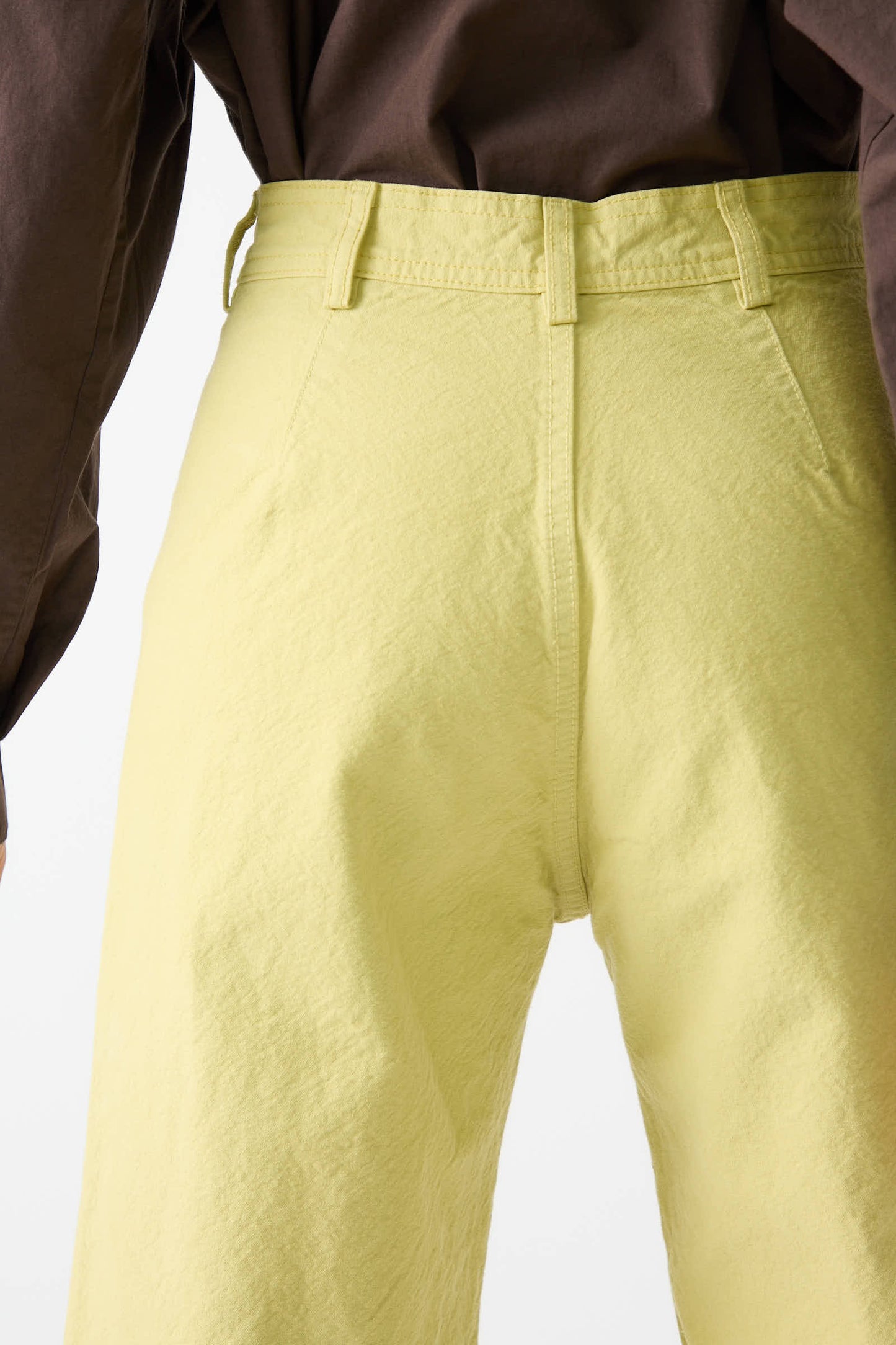 Close-up of the back side of a person wearing Jesse Kamm's Organic Canvas Sailor Pant in Citroen and a brown top.