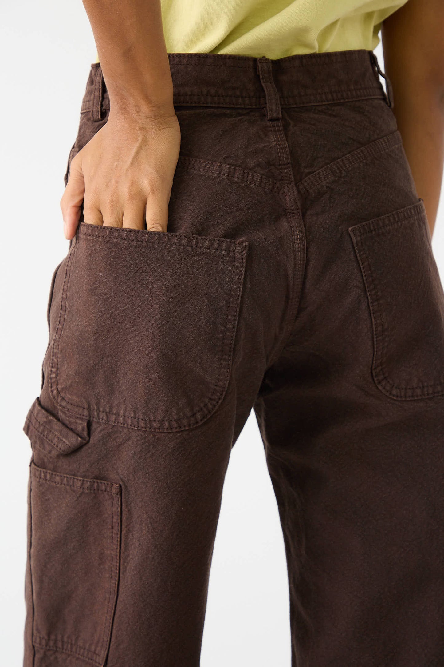 A person wearing the Jesse Kamm Organic Cotton Canvas Handy Pant in Raisin with their right hand placed in the back pocket.