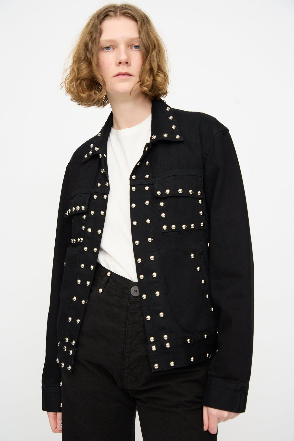A person wearing the Jesse Kamm Ranch Jacket in Black Overdye with Studs over a white t-shirt and black pants, standing against a plain white background.