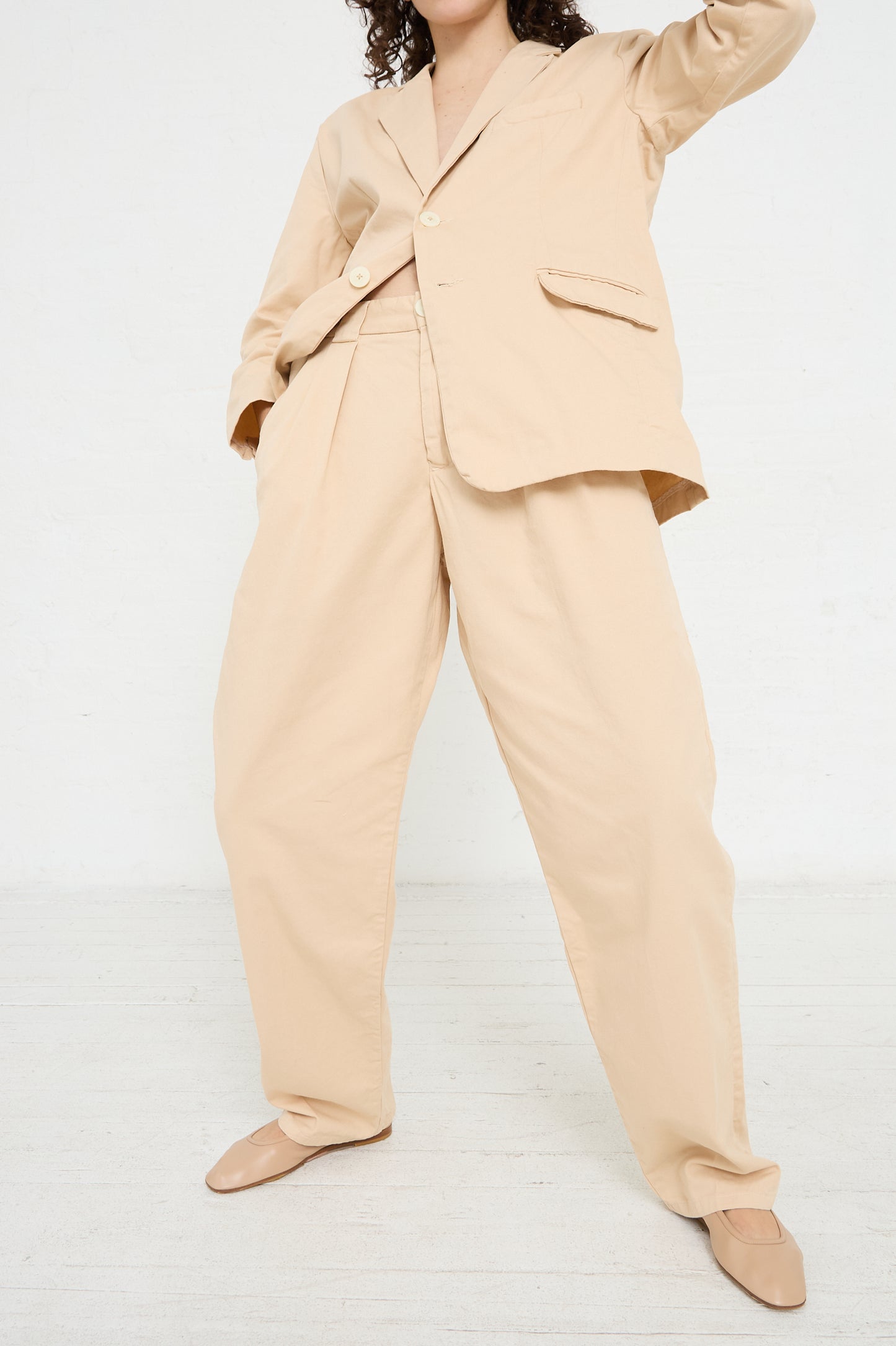 A woman wearing Jesse Kamm's The Trouser in Buff and a minimalist tan blazer with tapered legs.