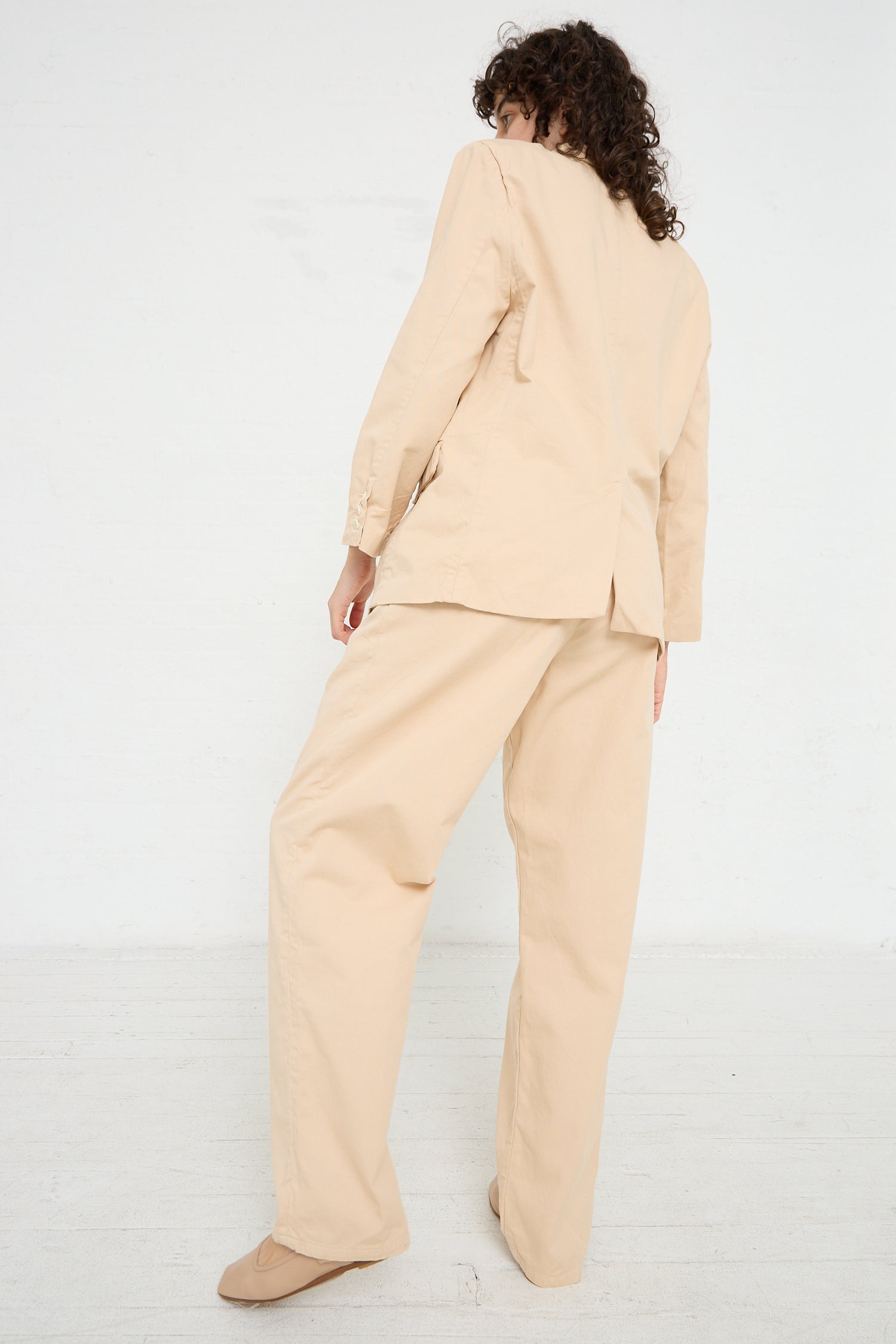 A woman wearing a Jesse Kamm Trouser in Buff suit with tapered leg pants made from organic cotton twill.