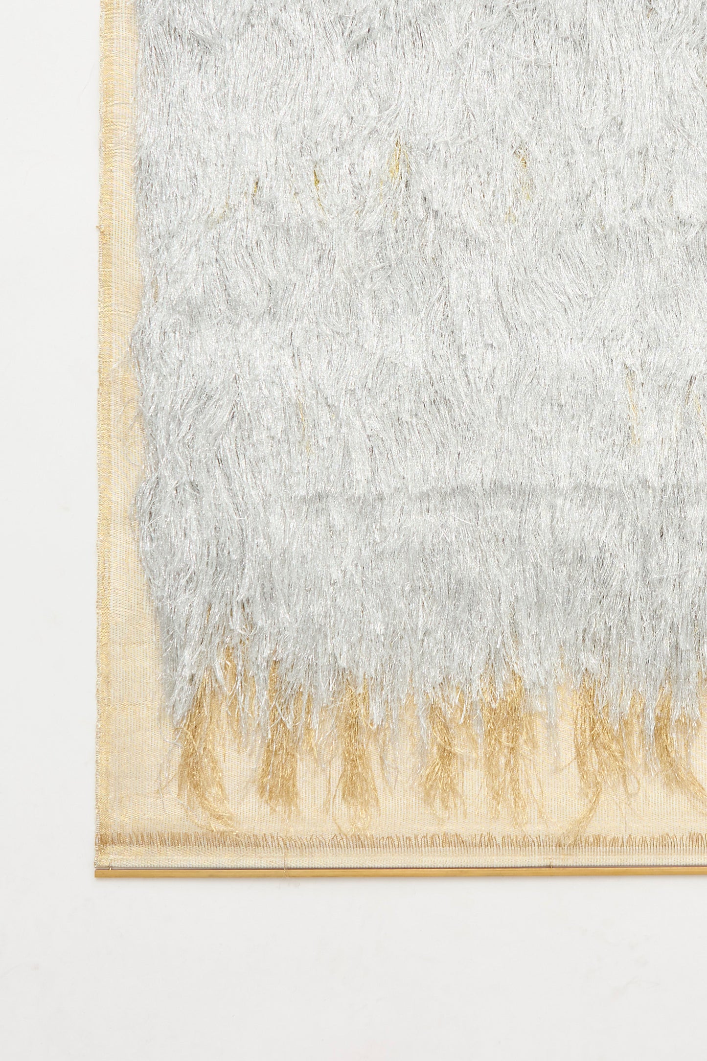 Close-up of the Great Awakener Weaving by Justine Ashbee, featuring silver and gold metallic fibers on a beige background, with a fringe edge and woven border. This rectangular wall hanging is handmade in the UK.