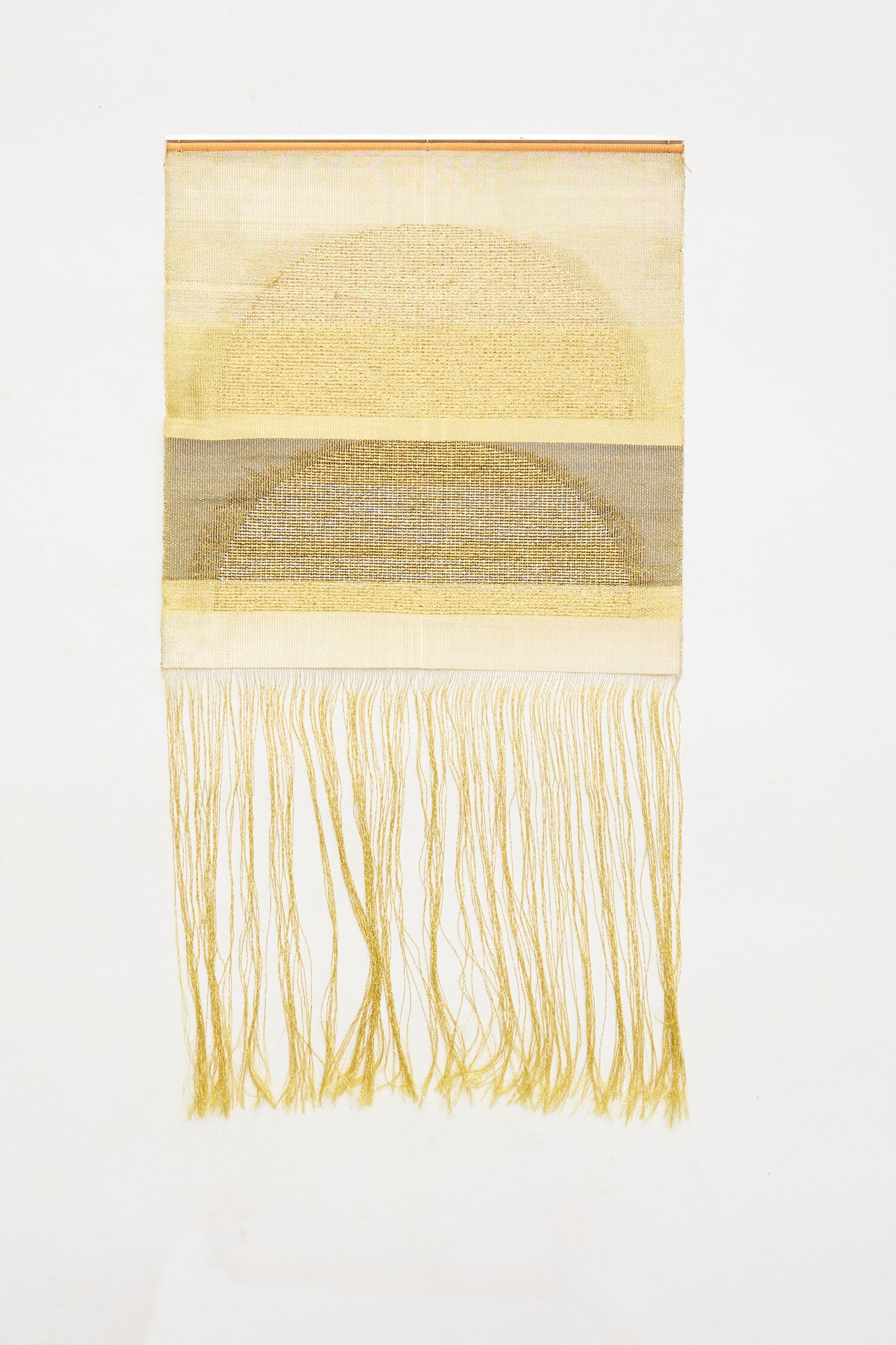 The Two Suns Rising Weaving by Justine Ashbee is a handmade rectangle wall hanging from the UK, showcasing a woven semicircle in muted yellow tones with long fringe cascading below.