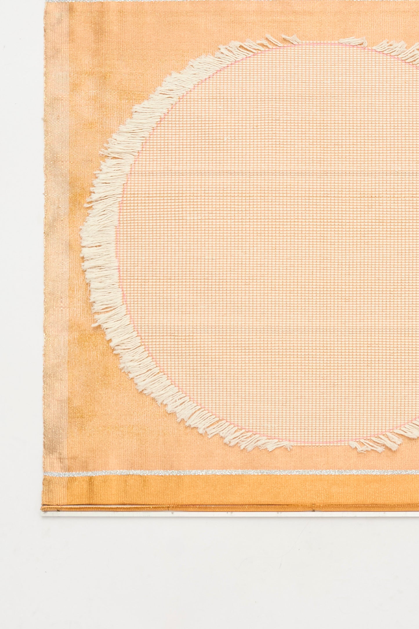 White Moon Weaving by Justine Ashbee is a handmade rectangular mat featuring a central circular pattern, frayed edge details, and a light orange-beige palette—crafted in the UK.